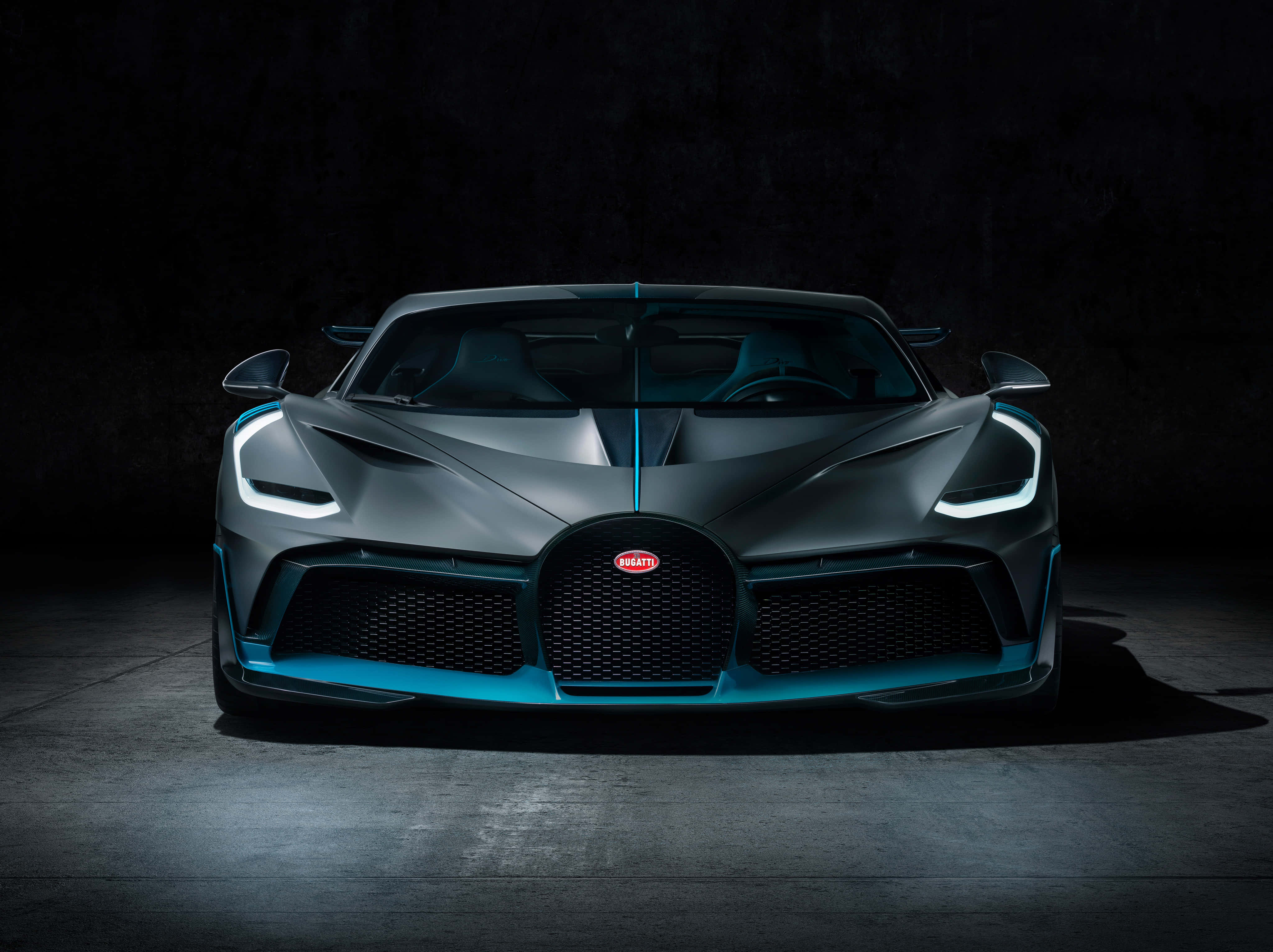 Best Bugatti 桌布 壁紙 — 一輛時尚的啞光灰色Bugatti超跑，帶有發光的藍色點綴，在戲劇性的攝影棚燈光下直視前方。