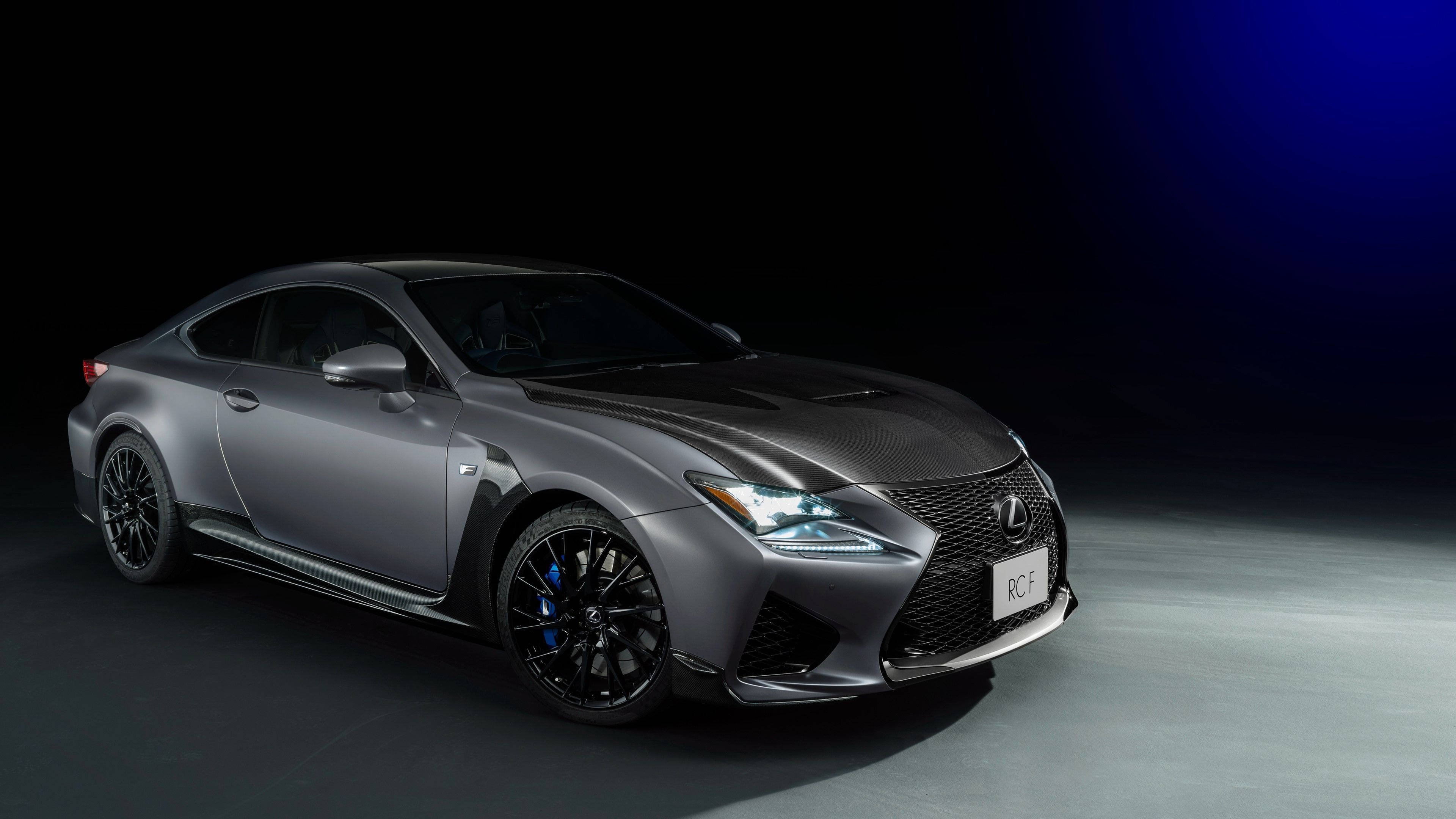 Lexus 標誌 桌布 壁紙 — 一輛時尚的啞光灰色Lexus RC F跑車在深色漸變背景的攝影棚燈光下閃耀。