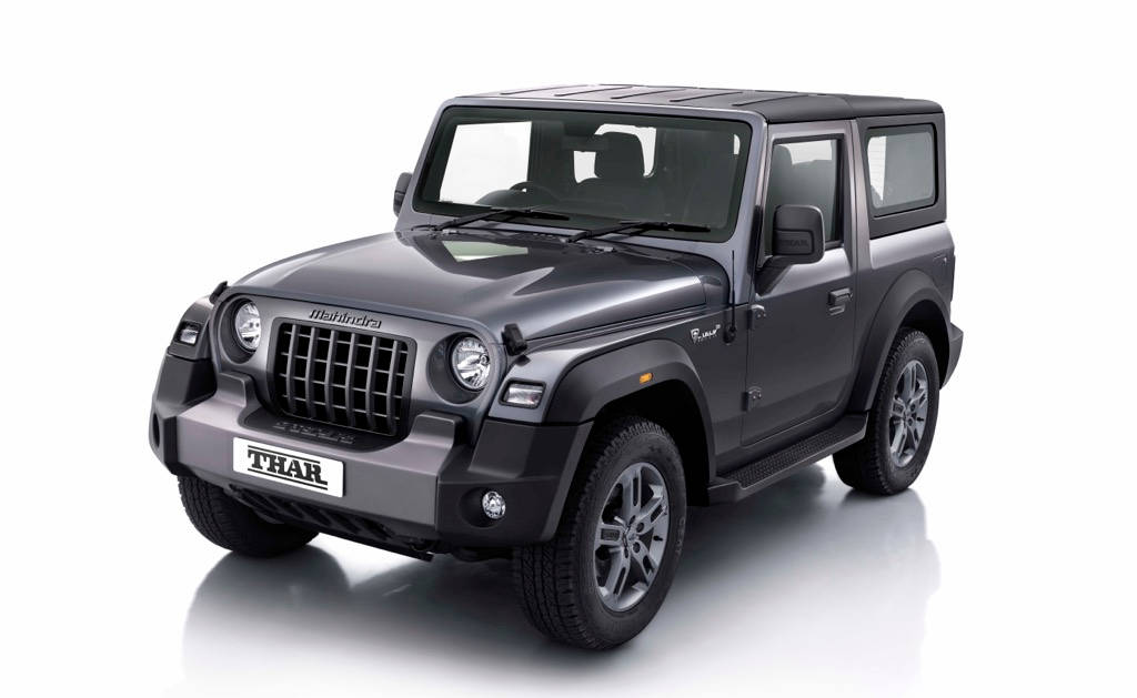 吉普 桌布 壁紙 — 一輛時尚的啞光灰色Mahindra Thar SUV停在反射白色攝影棚地板上，展現堅固設計與大膽姿態。