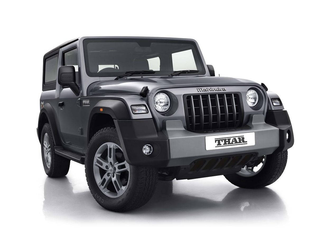 高清 桌布 壁紙 — 一輛時尚的啞光灰色Mahindra Thar SUV自信地站在反射性白色攝影棚地板上，展示其堅固的設計和醒目的大膽前格柵。