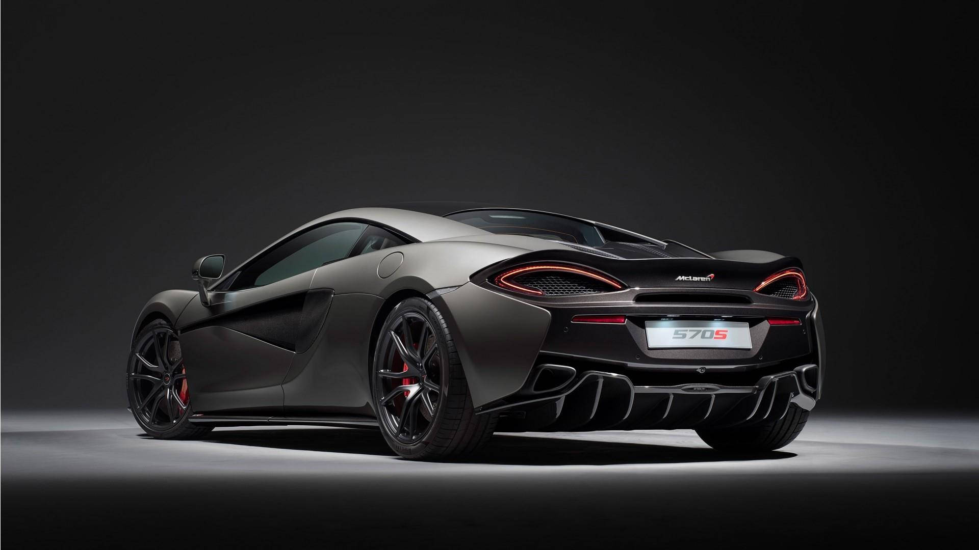 麥拉倫 桌布 壁紙 — 一輛時尚的啞光灰色McLaren 570S跑車，帶有發光的紅色尾燈，在黑暗背景下的戲劇性工作室聚光燈中展示。