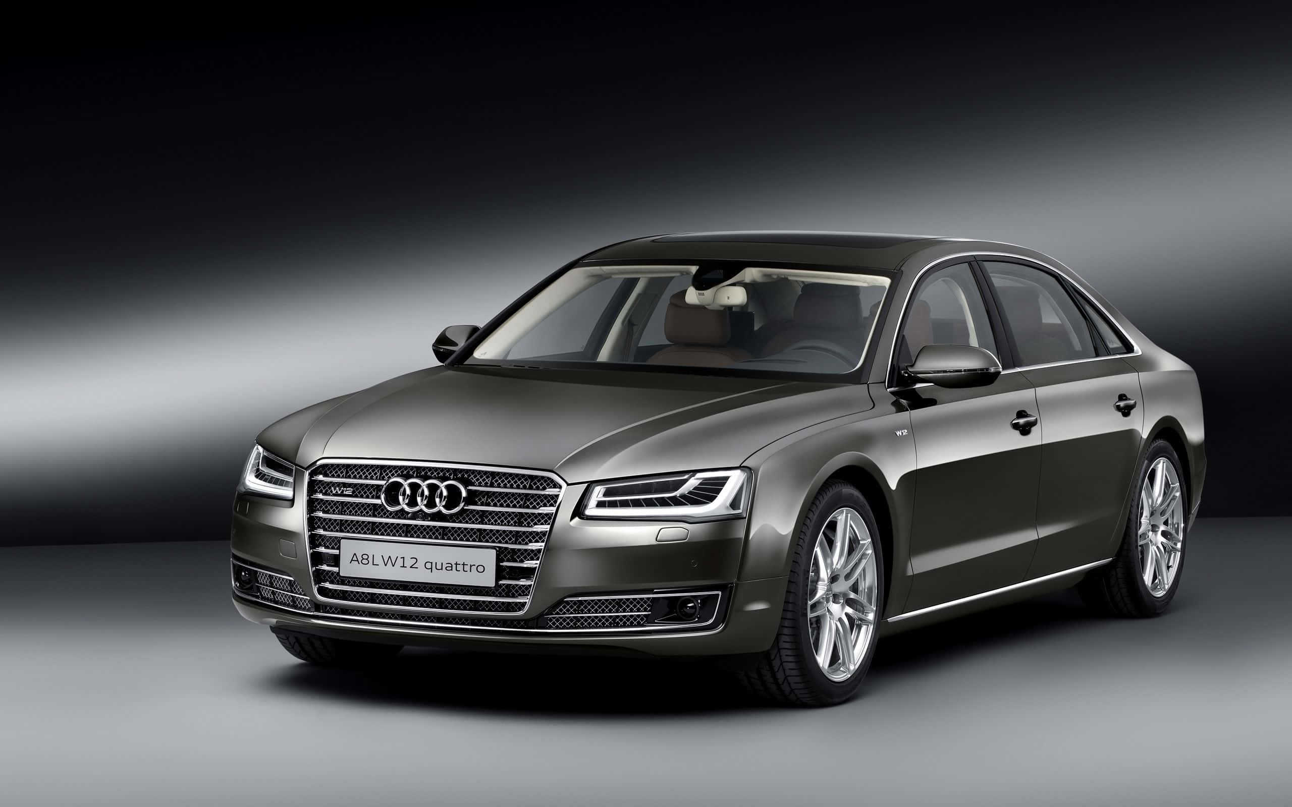 Audi S8 桌布 壁紙 — 一輛時尚的啞光灰色奧迪A8L W12 quattro轎車在工作室中展示，配有戲劇性的聚光燈和漸變灰色背景。