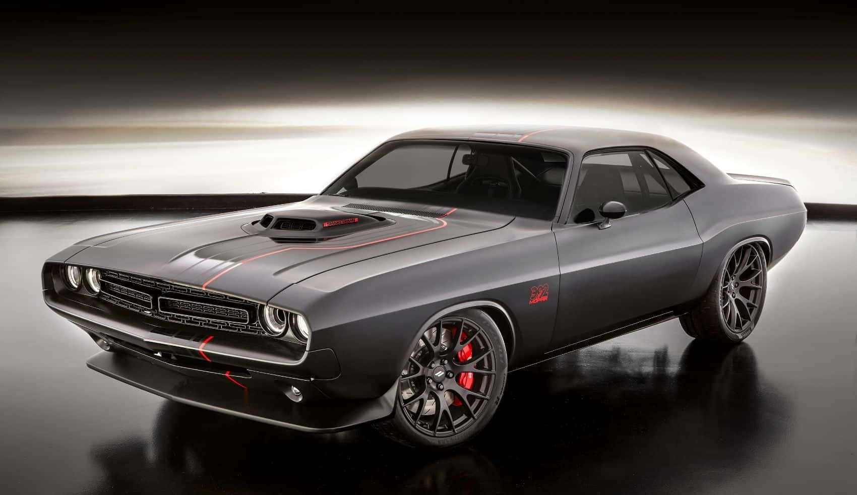 Dodge 桌布 壁紙 — 一輛時尚的啞光灰色道奇挑戰者，帶有紅色點綴和黑色輪轂，在反射地板上的工作室燈光下閃閃發光。