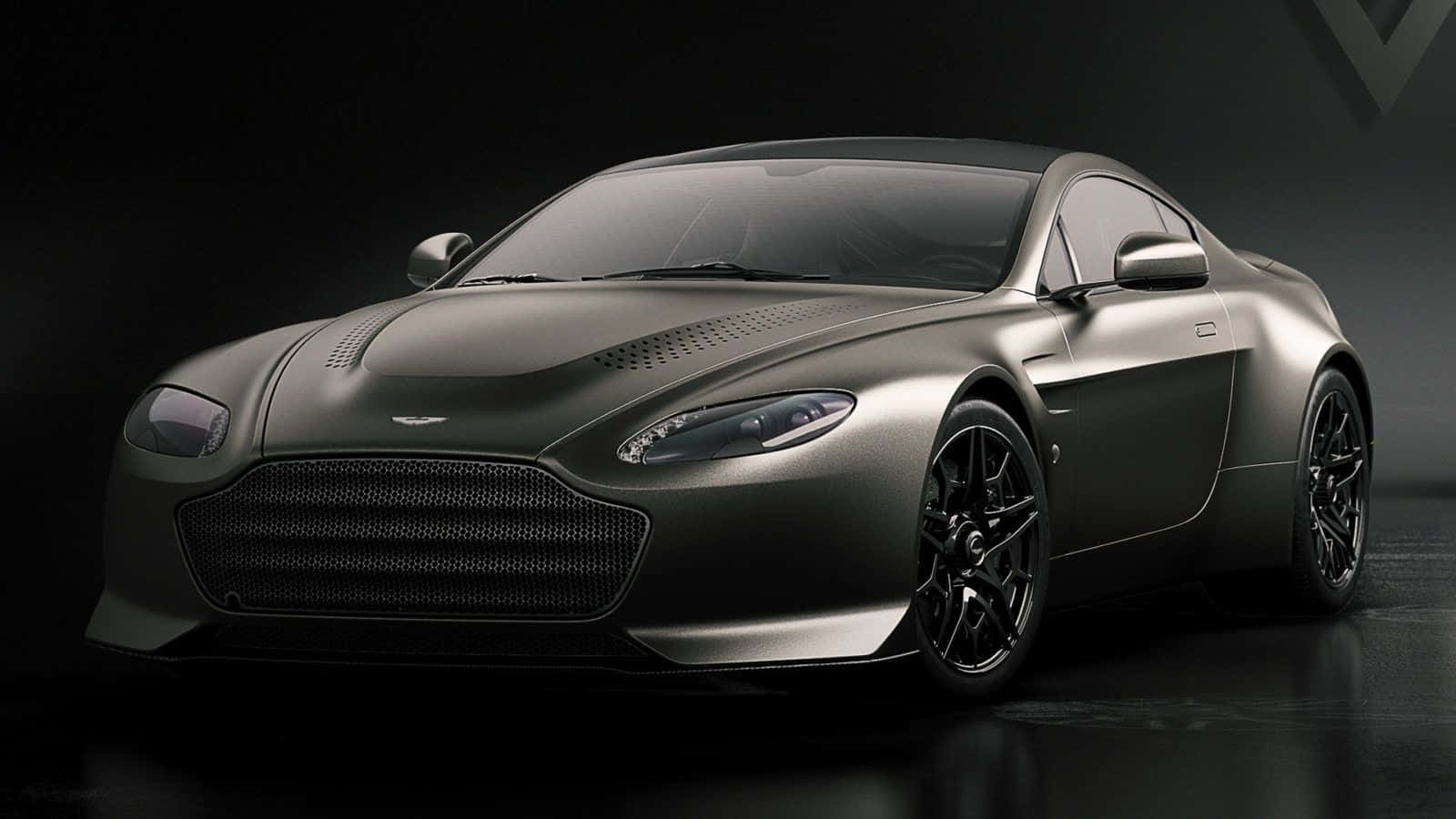 Aston Martin V12 Vantage 桌布 壁紙 — 一輛時尚的啞光灰色阿斯頓馬丁跑車在戲劇性的工作室燈光下，於深色背景中閃耀。