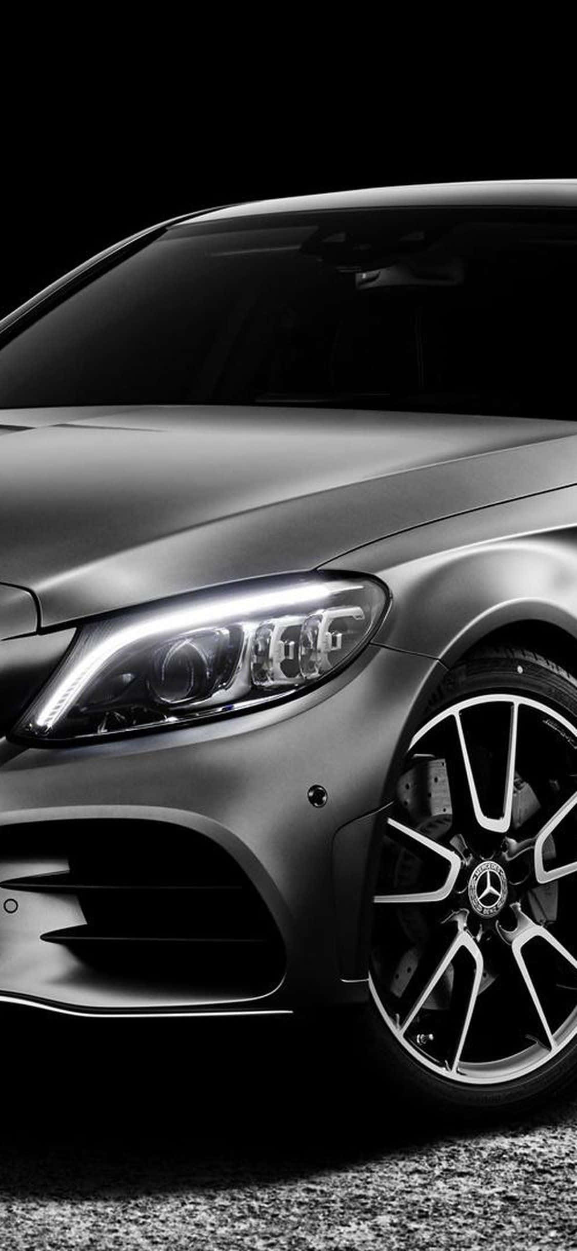 Mercedes 桌布 壁紙 — 一輛時尚的啞光銀色梅賽德斯-奔馳跑車，配備發光頭燈和合金輪圈，背景為深色。