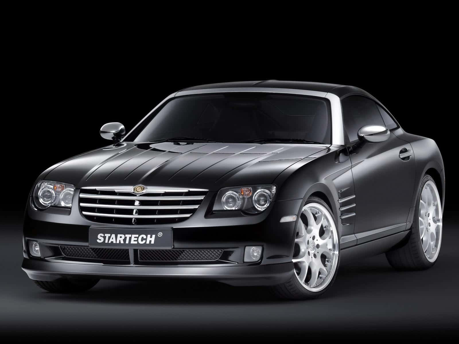 Chrysler Crossfire 桌布 壁紙 — 一輛時尚的啞光黑色Startech跑車，帶有銀色點綴和定制輪轂，在深色工作室背景下擺拍。
