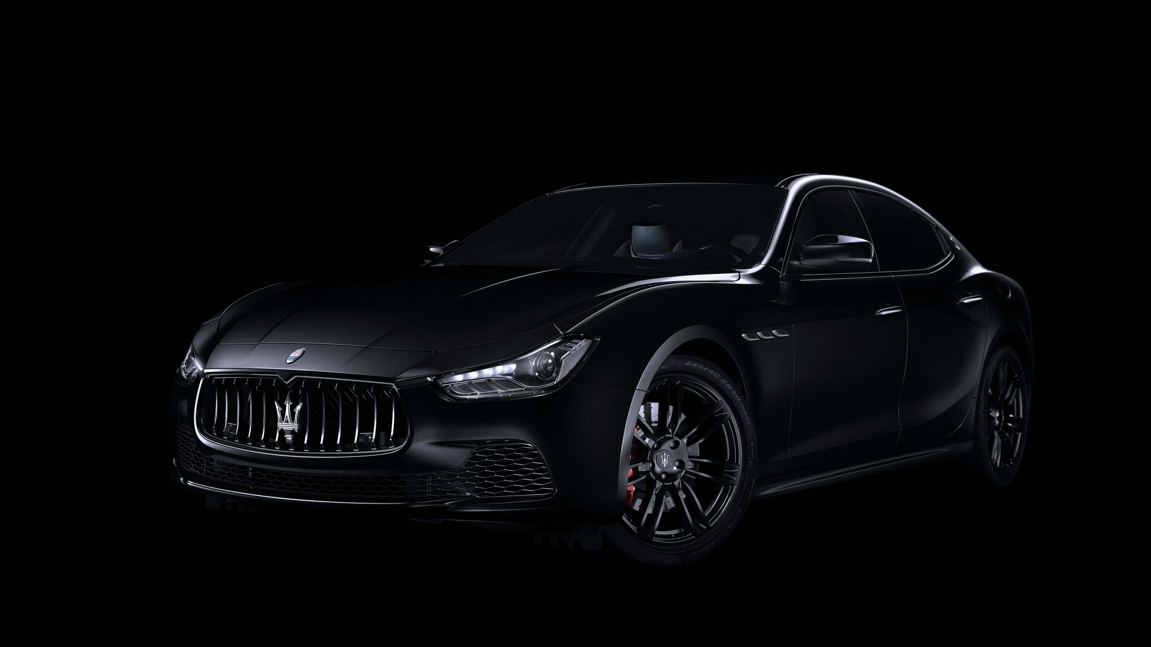 Black Car 4K 桌布 壁紙 — 一輛時尚的啞光黑色瑪莎拉蒂跑車在純黑色背景下的攝影棚燈光中閃耀。