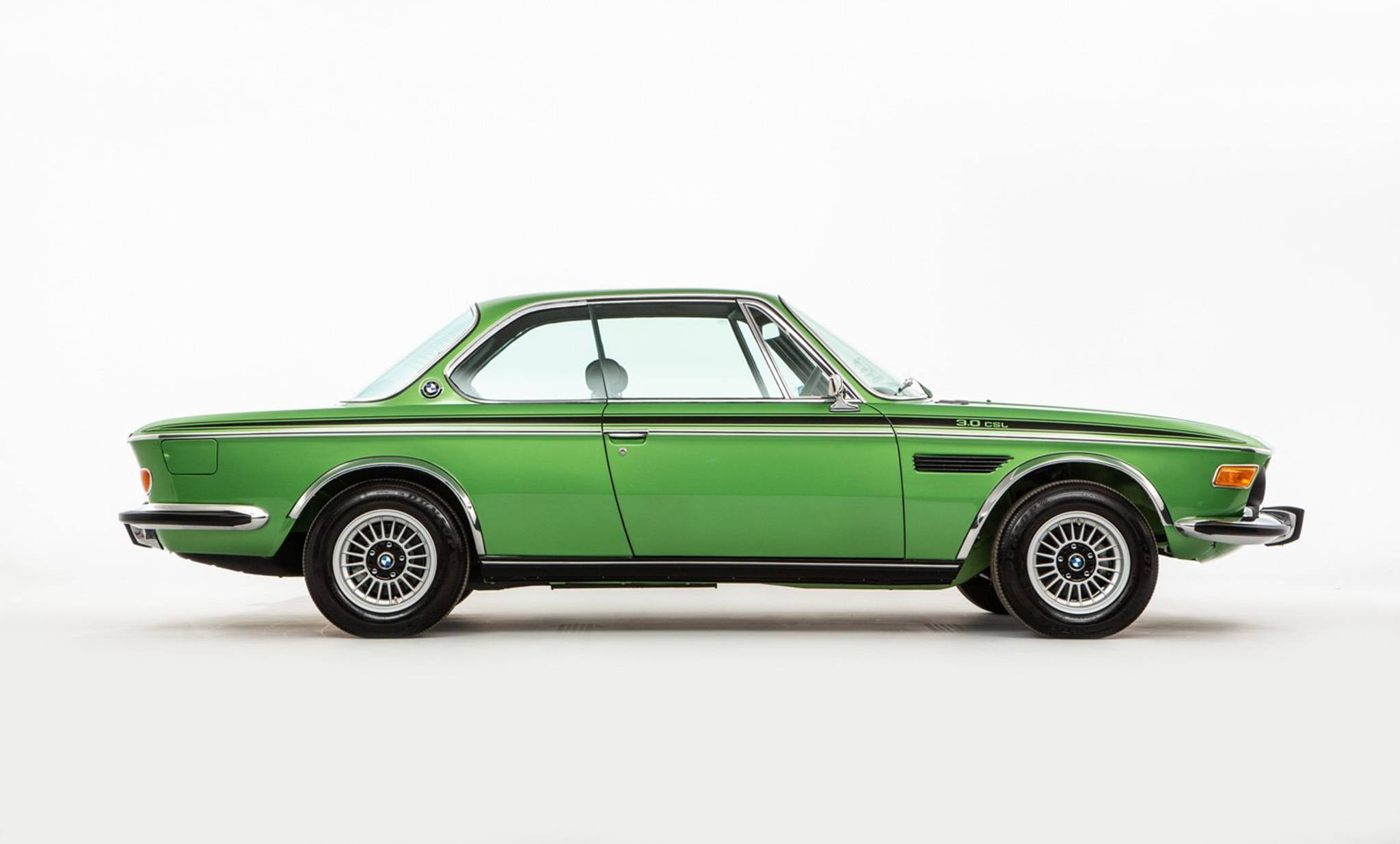 classic bmw 桌布 壁紙 — 一輛時尚的復古綠色BMW雙門轎跑車，帶有鍍鉻飾邊和鋼絲輪，在純淨的攝影棚燈光下展示。