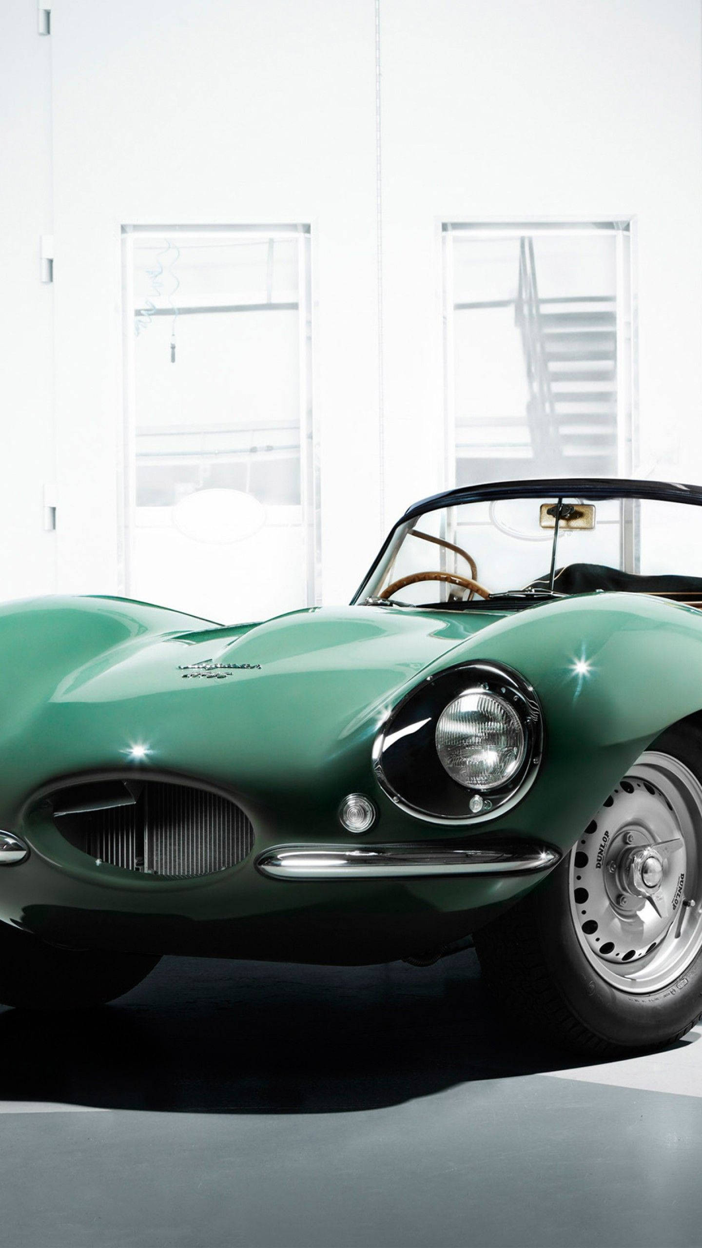 美洲豹汽車 桌布 壁紙 — 一輛時尚的復古綠色Jaguar E-Type跑車在簡約的白色空間中，在明亮的攝影棚燈光下閃閃發光。