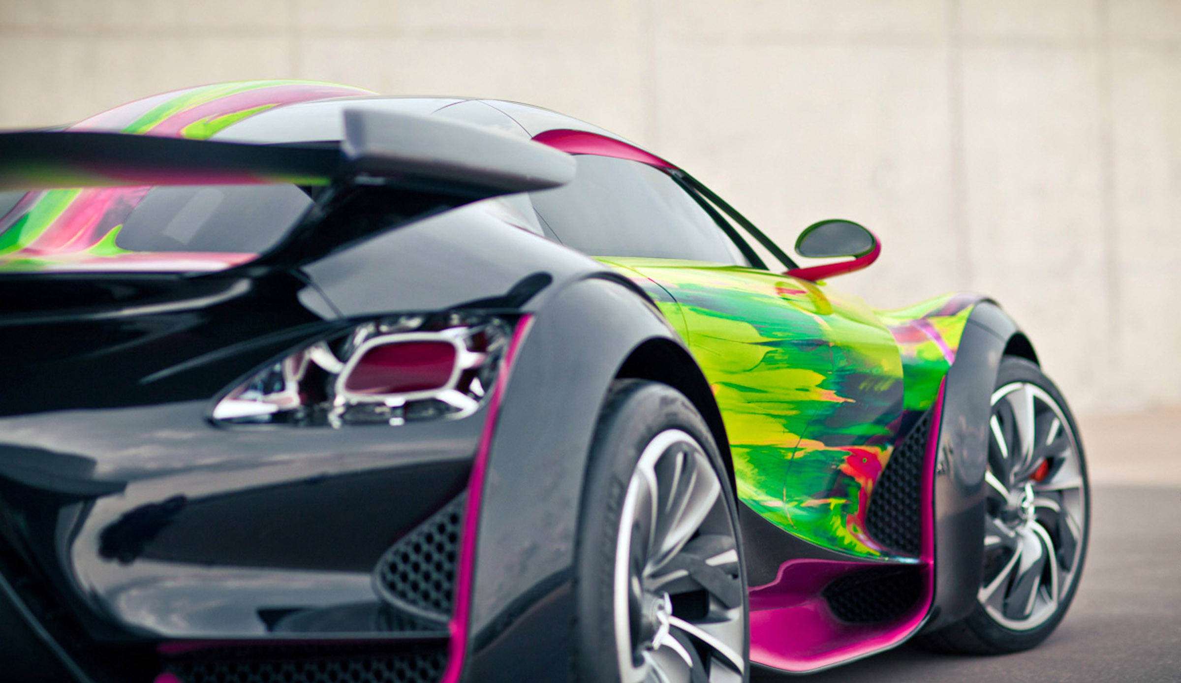 Citroen 桌布 壁紙 — 一輛時尚的未來主義跑車，帶有充滿活力的螢光綠色和粉紅色油漆點綴，停放在樸素的混凝土牆前。