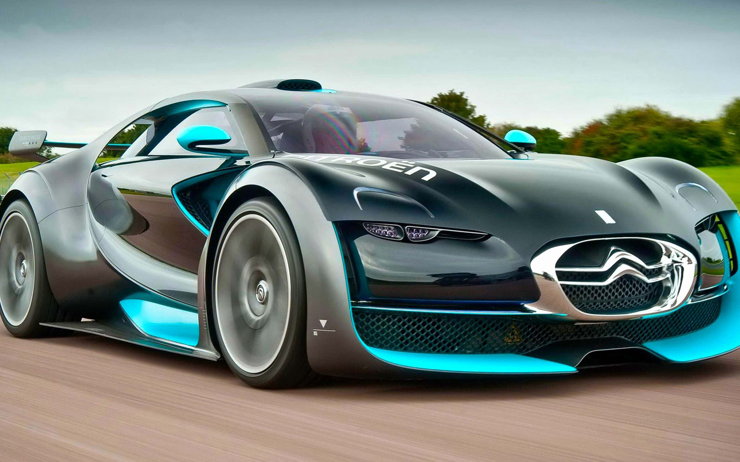 Top 10 Car 桌布 壁紙 — 一輛時尚的未來主義跑車，帶有發光的藍色裝飾，在綠色景觀中的道路上飛馳。