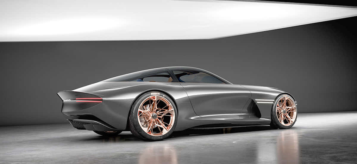 Genesis Essentia 桌布 壁紙 — 一輛時尚的未來主義跑車，配備玫瑰金輪圈和消光灰色車身，在攝影棚燈光下閃耀。
