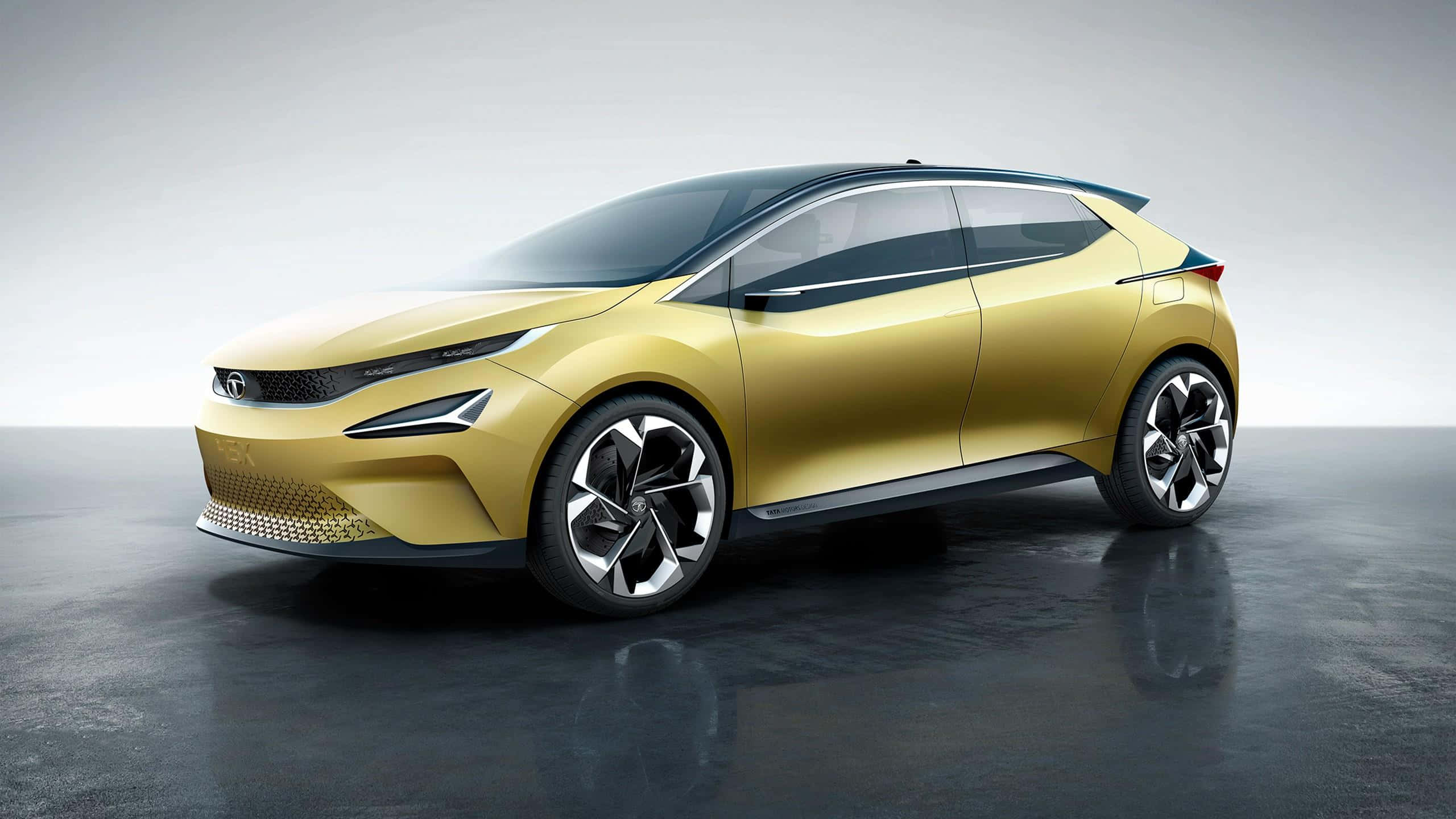 Tata Motors 桌布 壁紙 — 一輛時尚的未來主義金色汽車，帶有黑色飾邊和時尚車輪，停在反光的灰色地板上，背景是簡約的工作室背景。