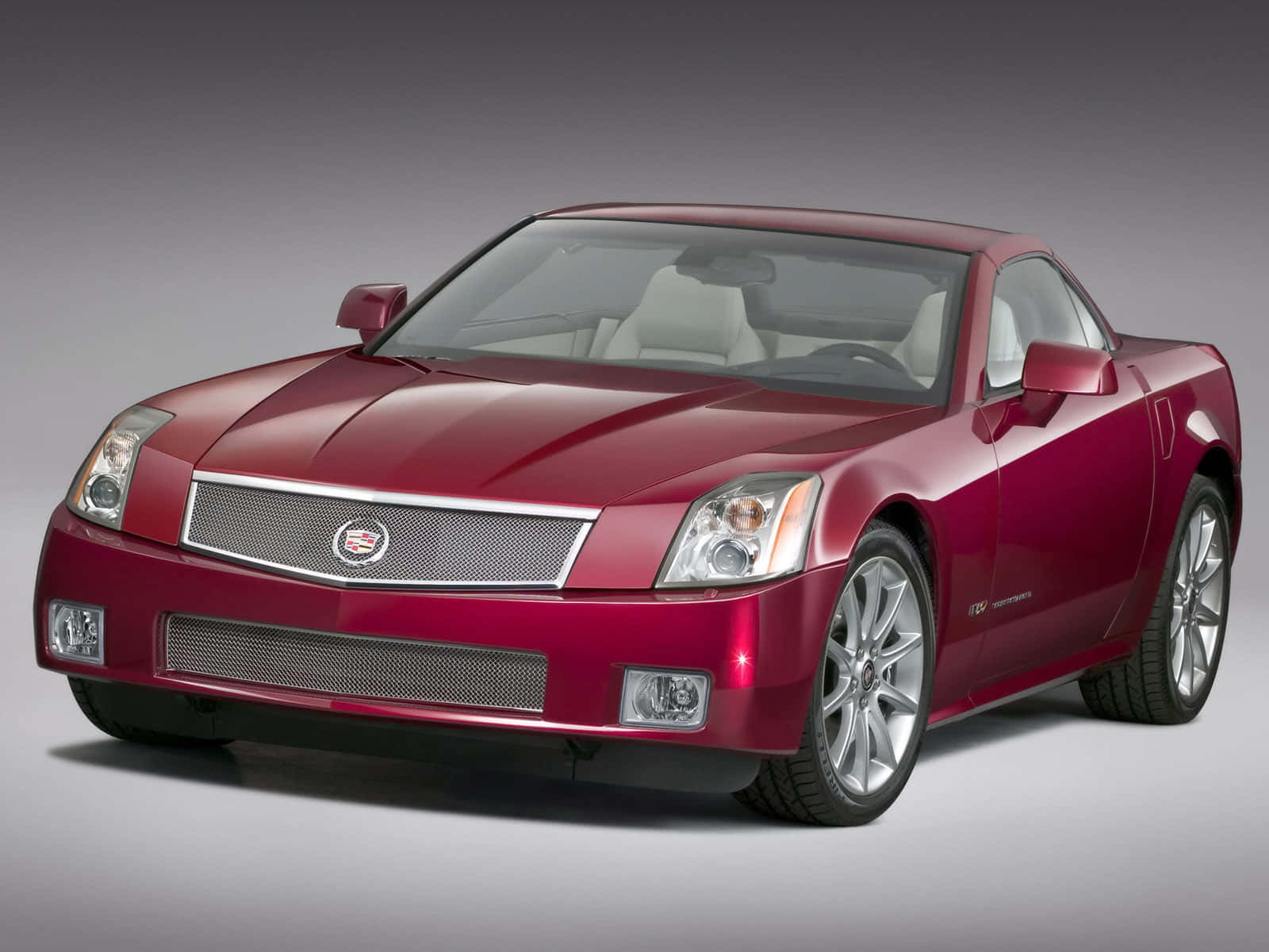 Cadillac Xlr 桌布 壁紙 — 一輛時尚的栗色Cadillac XLR跑車，配備銀色輪圈和白色內裝，在柔和燈光的攝影棚中展示。