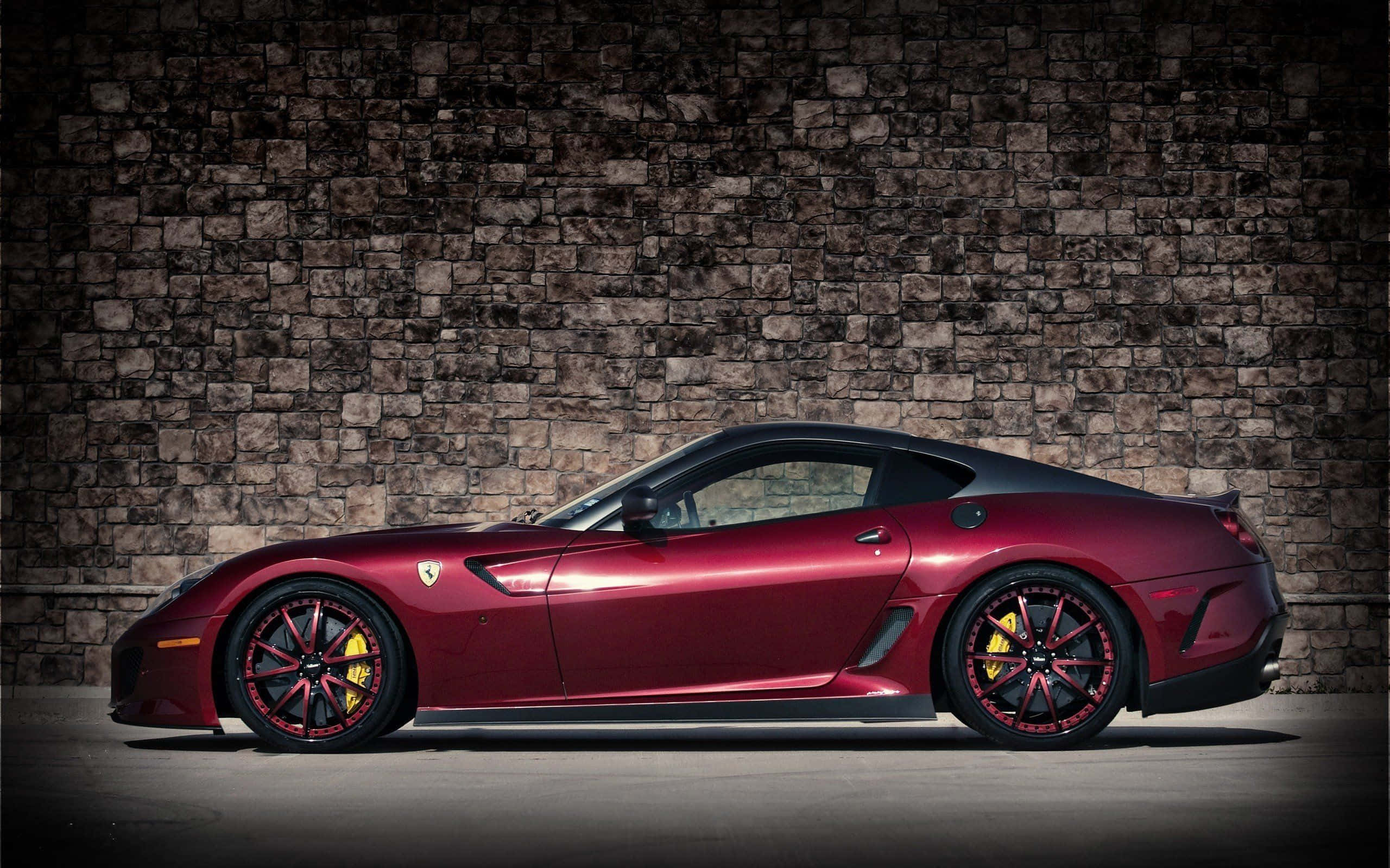 Ferrari 599 Gtb Fiorano 桌布 壁紙 — 一輛時尚的栗色法拉利跑車，帶有黃色制動卡鉗，側面立於有紋理的石牆前。