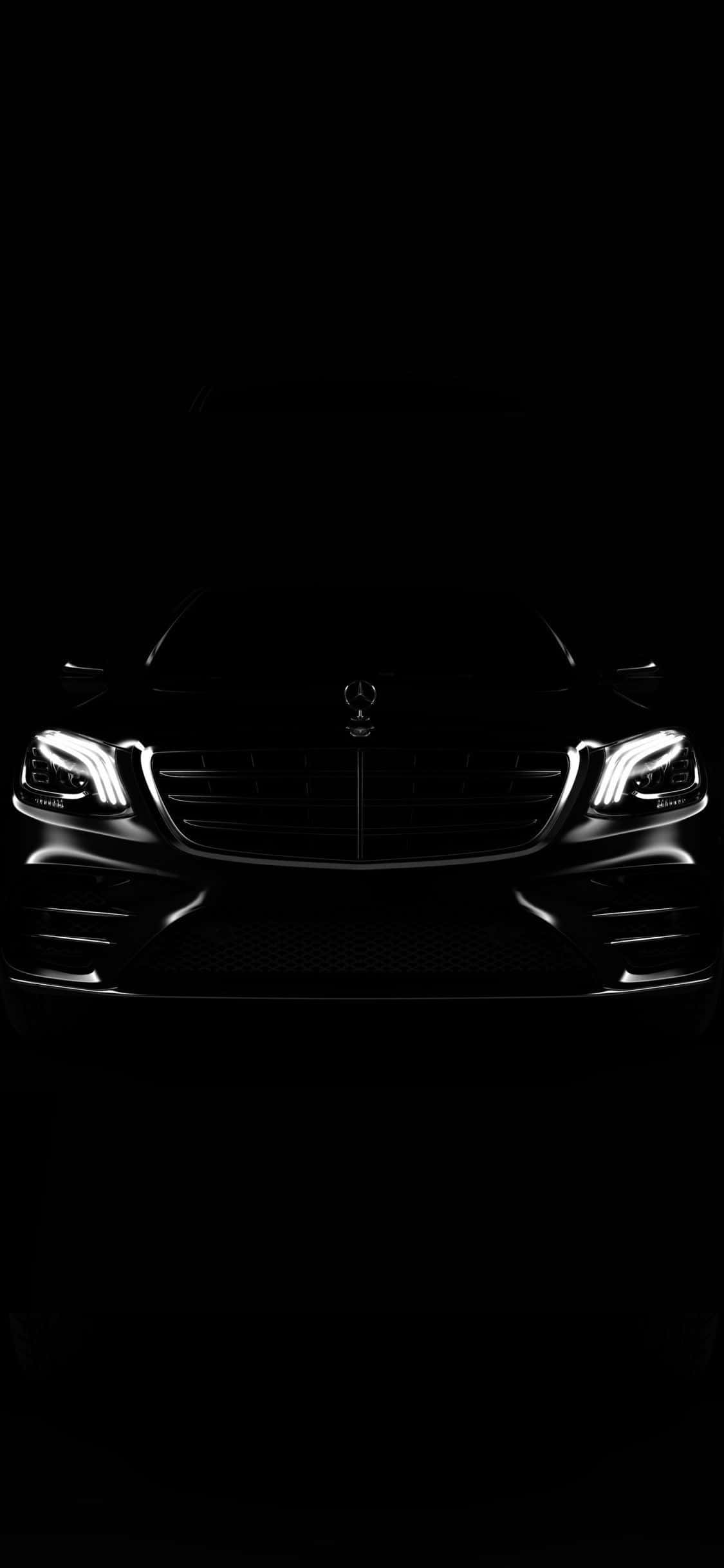 Mercedes 桌布 壁紙 — 一輛時尚的梅賽德斯-奔馳汽車前部，在漆黑背景下被發光的車頭燈照亮。