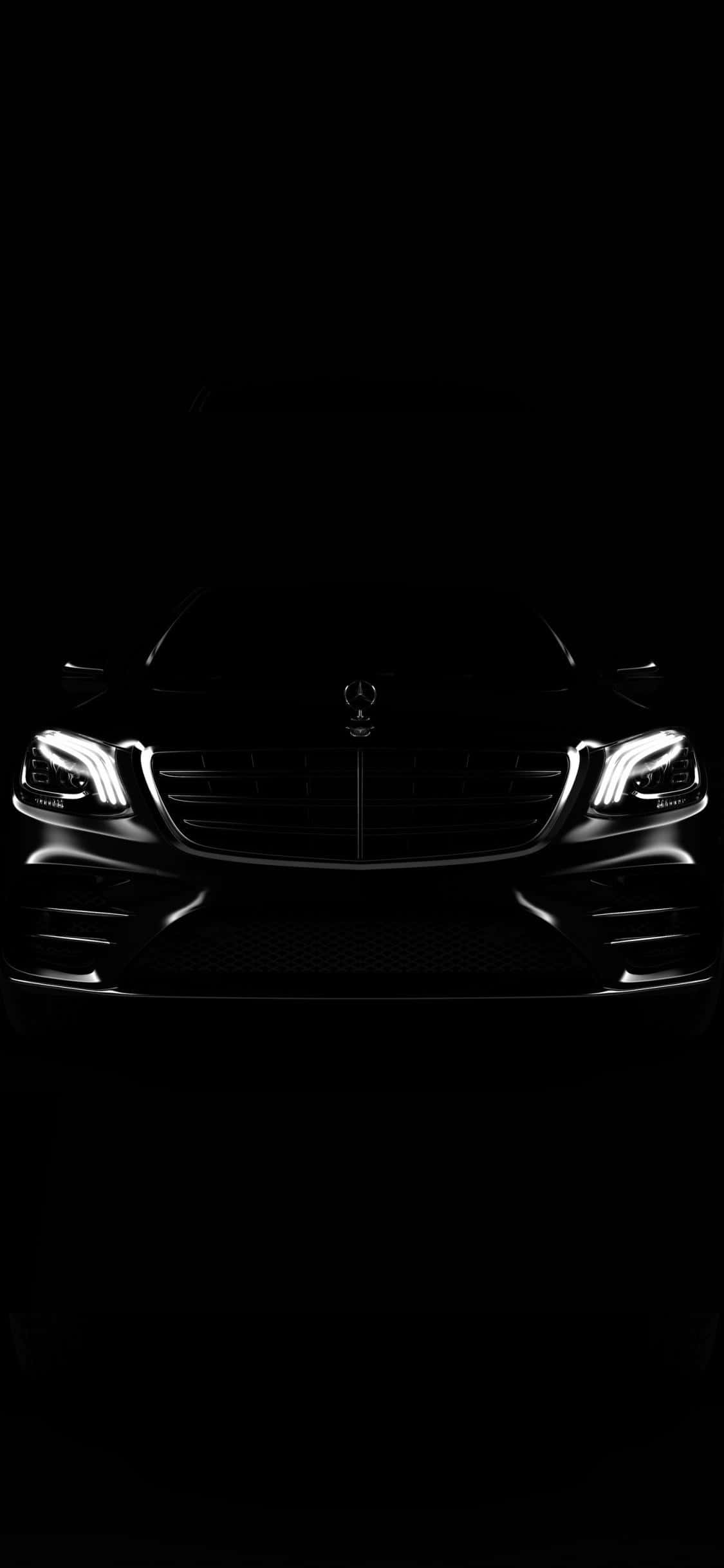 Mercedes 桌布 壁紙 — 一輛時尚的梅賽德斯-奔馳汽車的前格柵和車頭燈在漆黑的背景下明亮發光。