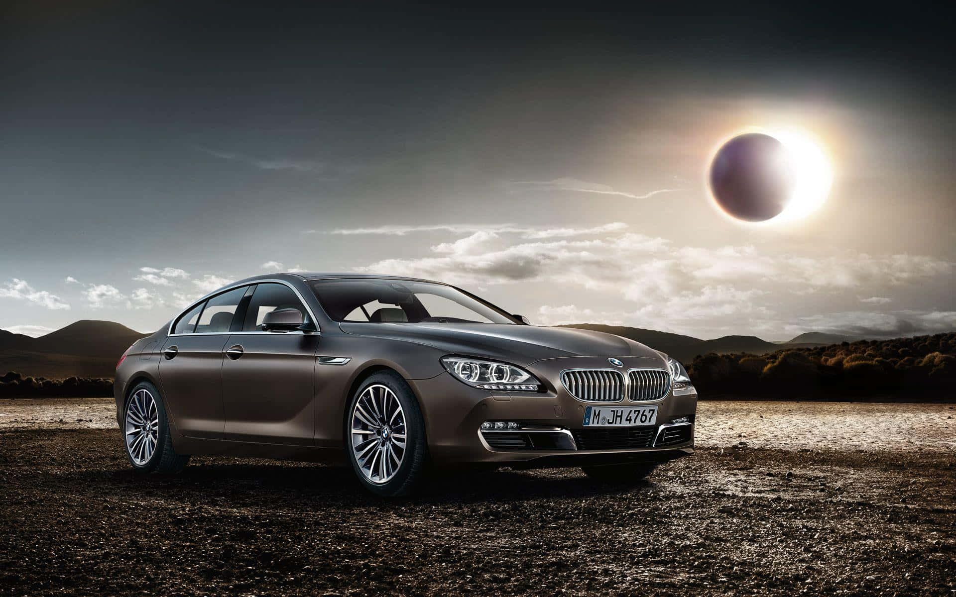 Bmw 6 Series 桌布 壁紙 — 一輛時尚的棕色BMW轎車停泊在泥地上，背景是戲劇性的日食、烏雲和遠山。