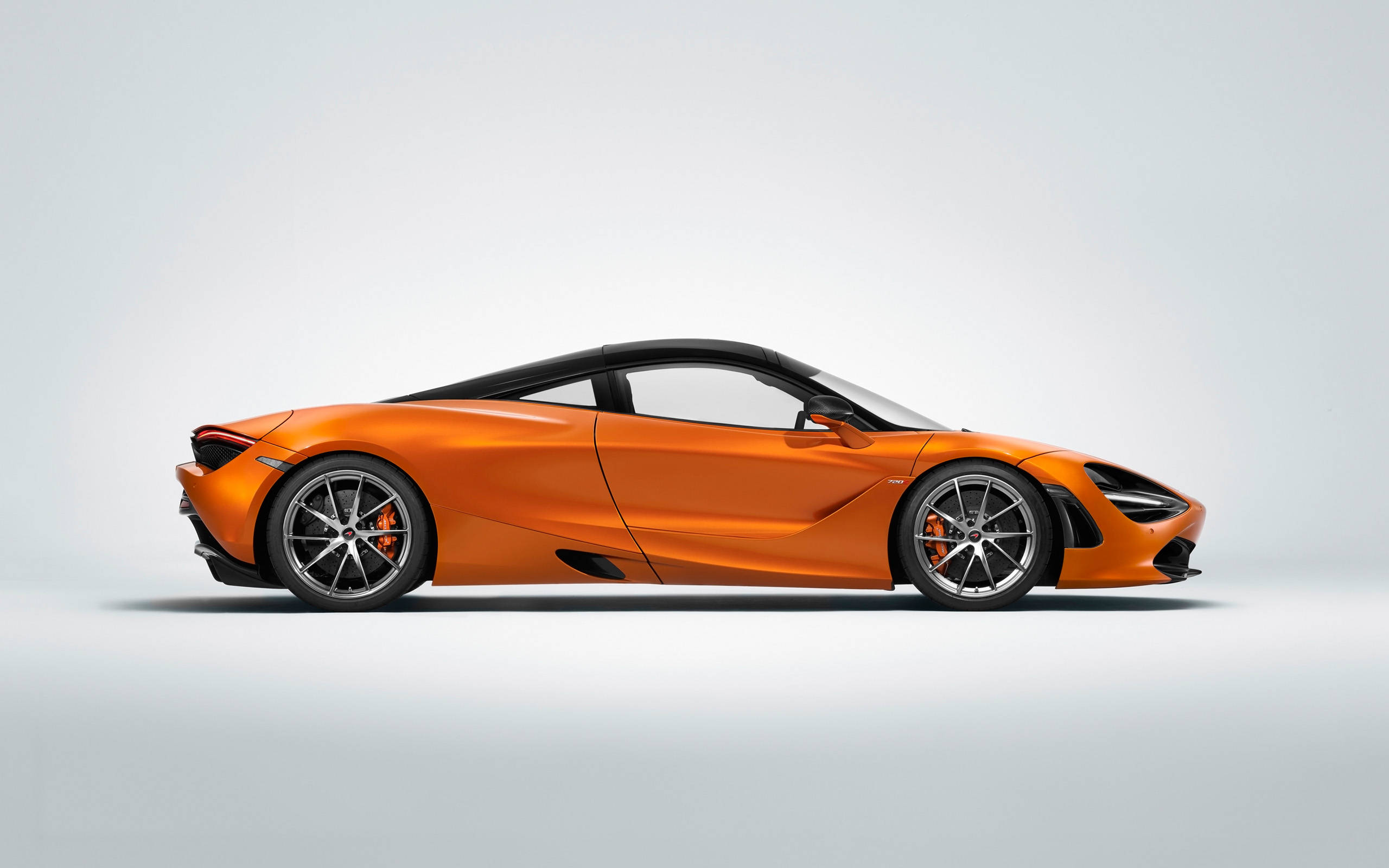 mclaren 720s 4K 桌布 壁紙 — 一輛時尚的橙色McLaren 720S跑車，在極簡的淺灰色工作室背景下以側面展示。