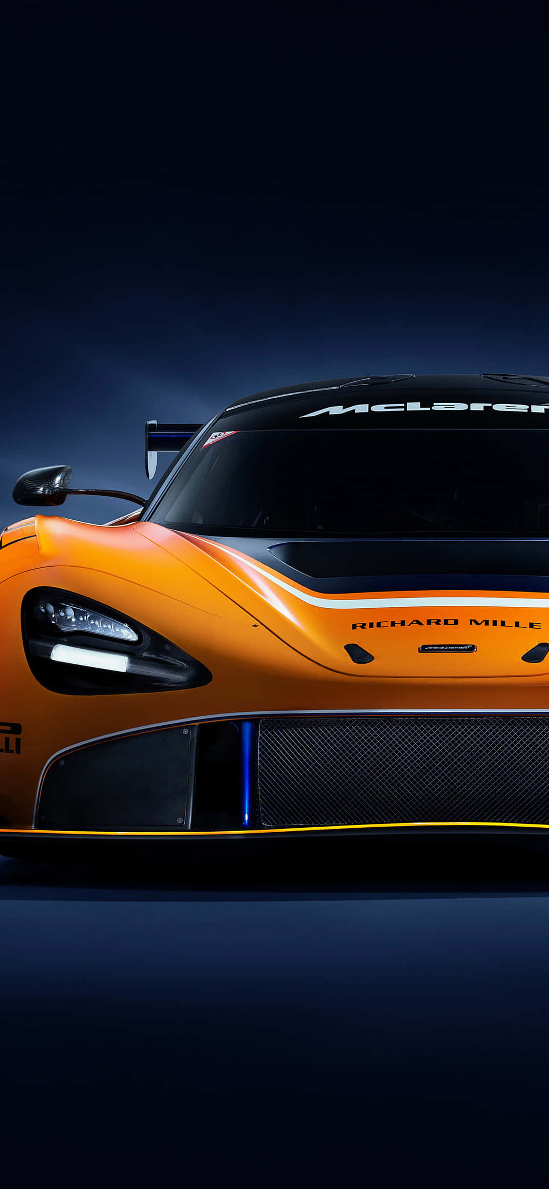 跑車 桌布 壁紙 — 一輛時尚的橙色McLaren賽車，帶有黑色飾邊和發光的藍色燈光，在黑暗背景下以戲劇性的低角度拍攝。
