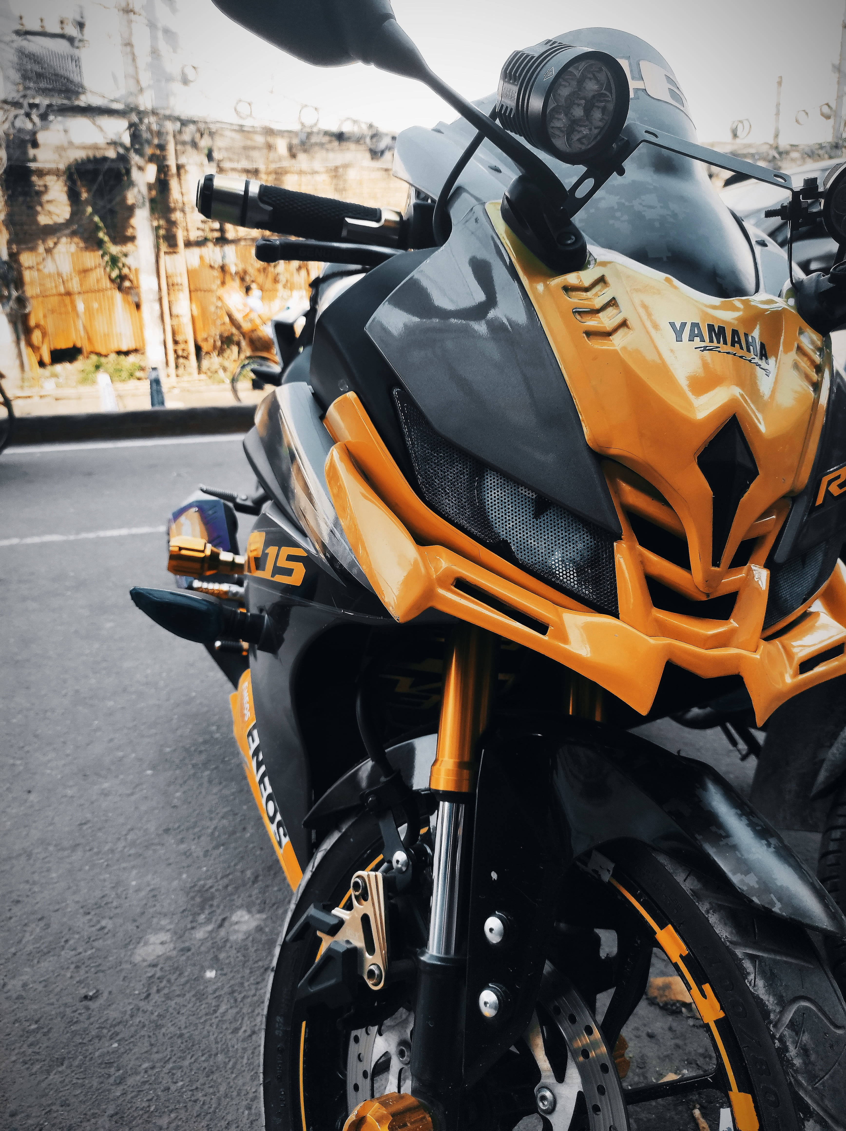 桌布 壁紙 — 一輛時尚的橙色和黑色Yamaha R15運動機車停泊在粗糙的城市街道上的特寫。