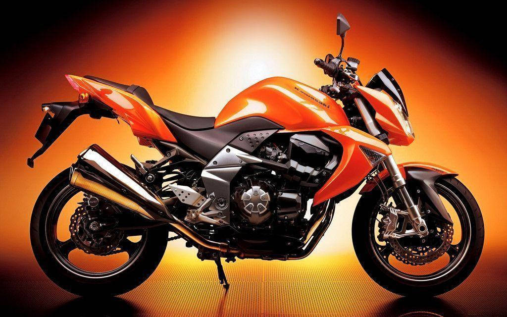 Kawasaki Desktop 桌布 壁紙 — 一輛時尚的橙色運動機車帶有鍍鉻裝飾，在耀眼的漸變橙色背景前蓄勢待發。