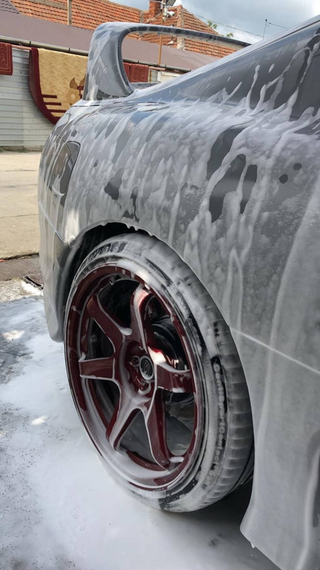 Wash 桌布 壁紙 — 一輛時尚的汽車被厚厚的白色肥皂泡覆蓋，正在戶外清洗，泡沫下方可見紅色輪圈。