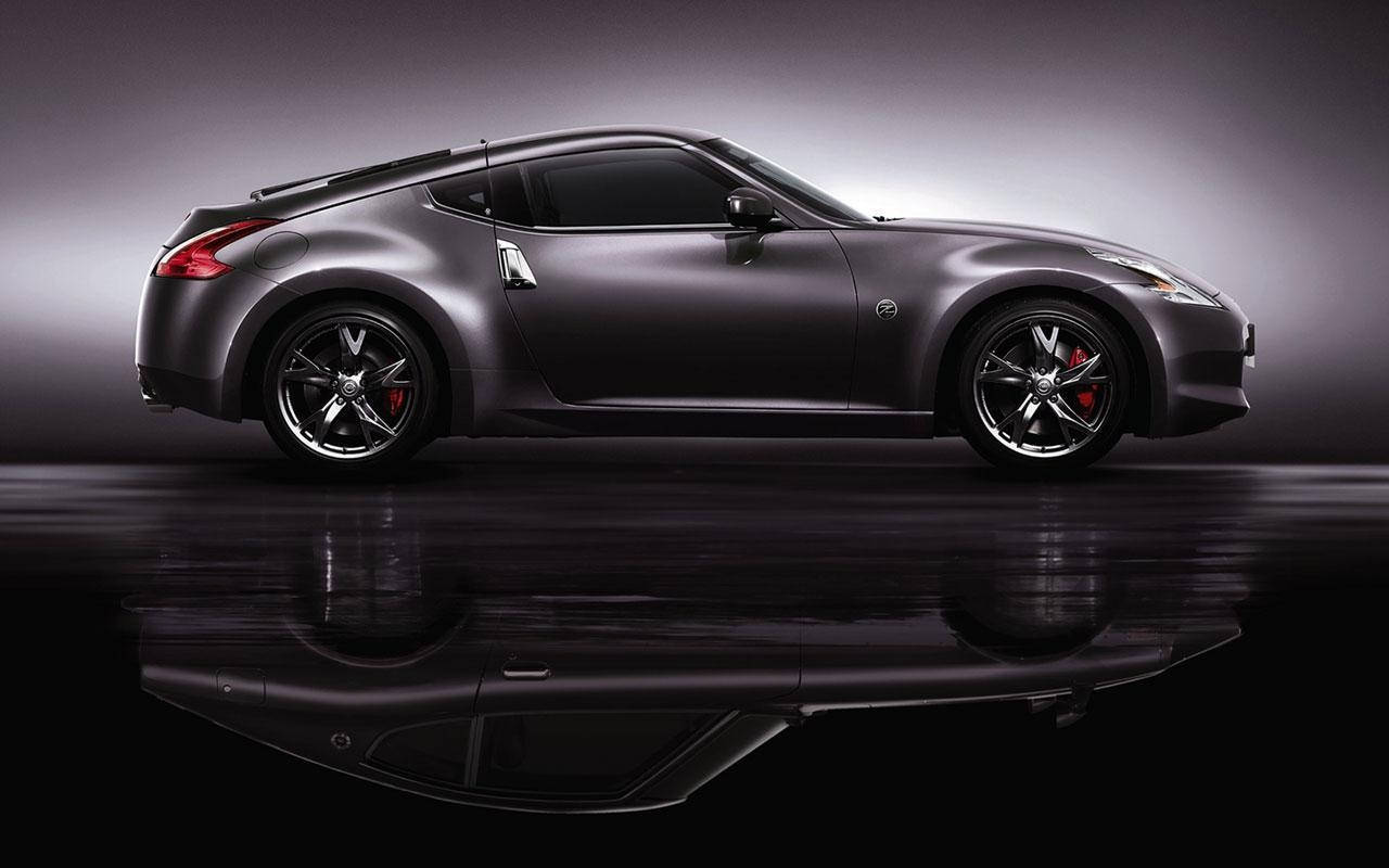 Nissan 350z 桌布 壁紙 — 一輛時尚的消光灰色跑車配備紅色制動卡鉗，在具有戲劇性燈光和反射地板的攝影棚中展示。