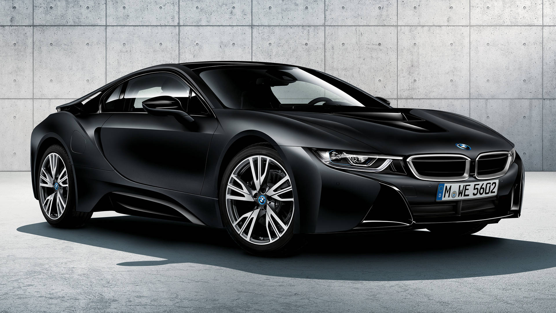 Black Bmw 桌布 壁紙 — 一輛時尚的消光黑色BMW i8跑車在明亮的日光下，停在簡約的混凝土牆前。