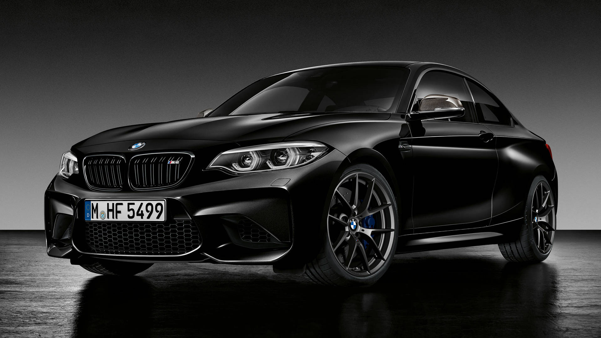Black Bmw 桌布 壁紙 — 一輛時尚的消光黑色BMW M2雙門轎跑車在攝影棚燈光下，在深色反光地板上閃閃發光。