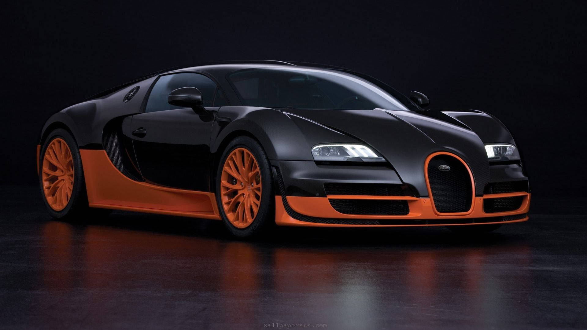 布加迪 桌布 壁紙 — 一輛時尚的消光黑色Bugatti Veyron，帶有鮮豔的橙色點綴和輪圈，在暗色反光地板上的攝影棚燈光下閃閃發光。