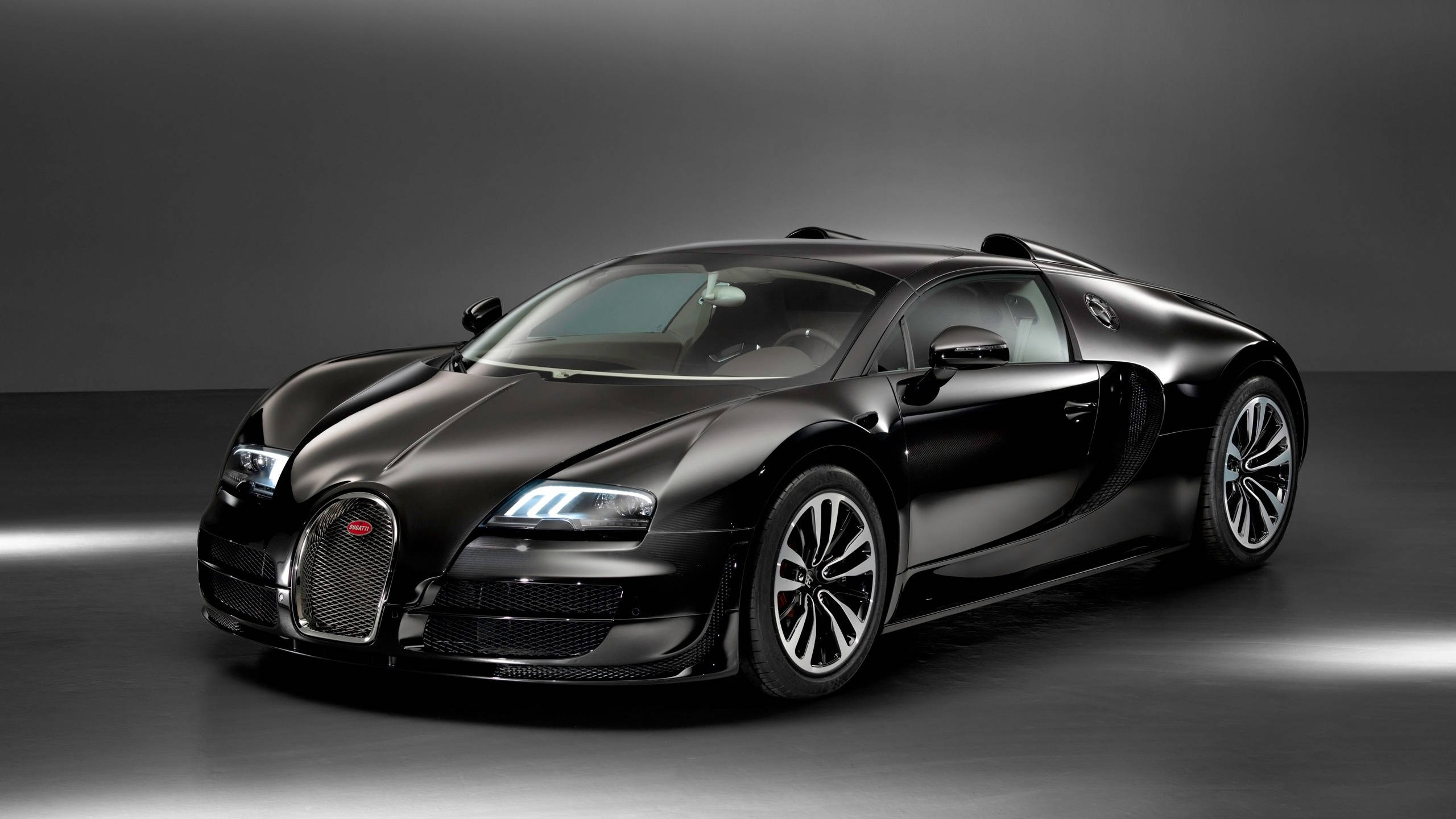 bugatti iPhone 桌布 壁紙 — 一輛時尚的消光黑色布加迪威龍跑車在攝影棚燈光下，在深灰色背景前閃耀。