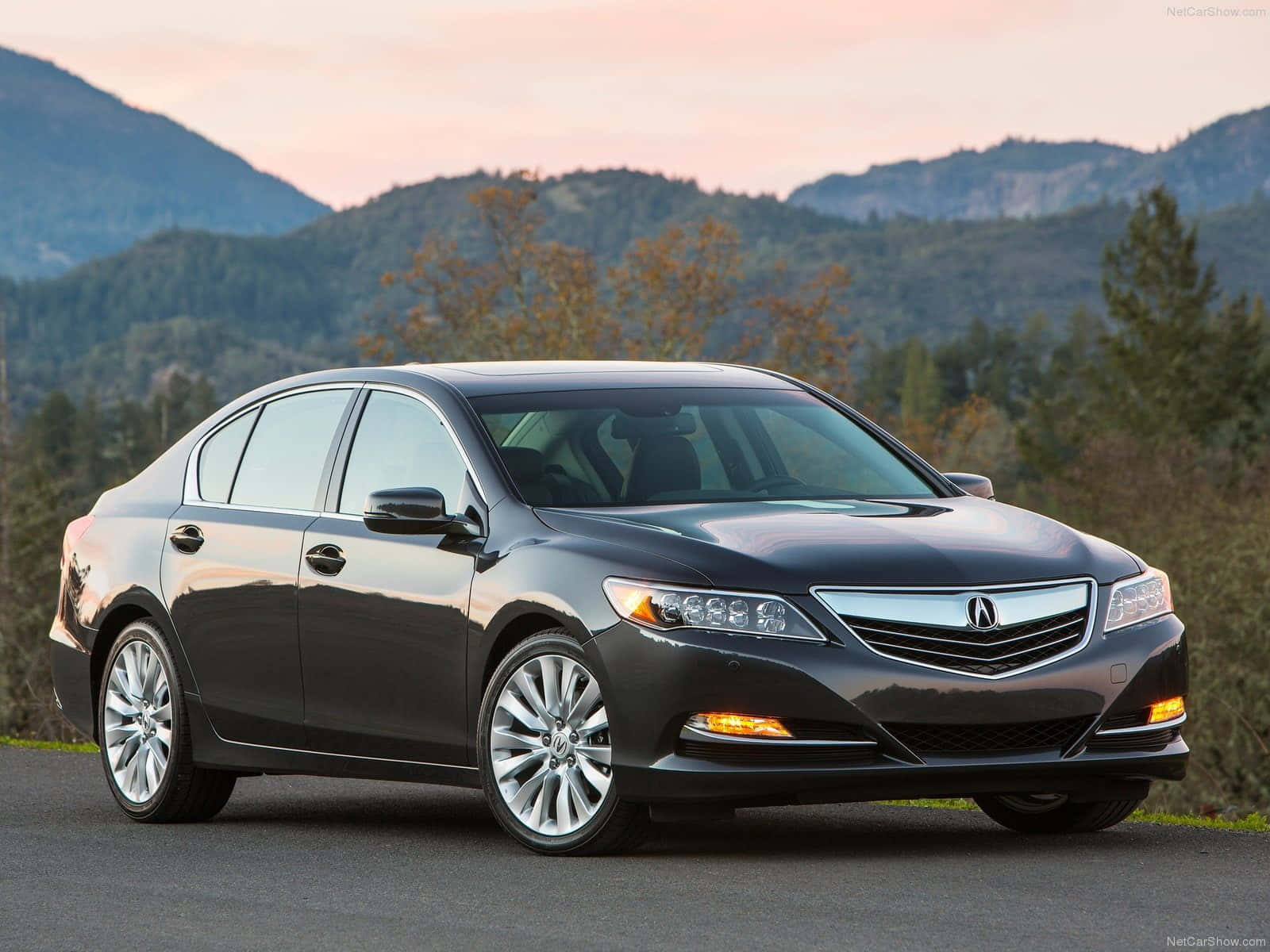 Acura Rlx 桌布 壁紙 — 一輛時尚的深灰色Acura轎車停泊在道路上，背景是山脈和秋樹，天空呈現柔和的粉紅色日落。