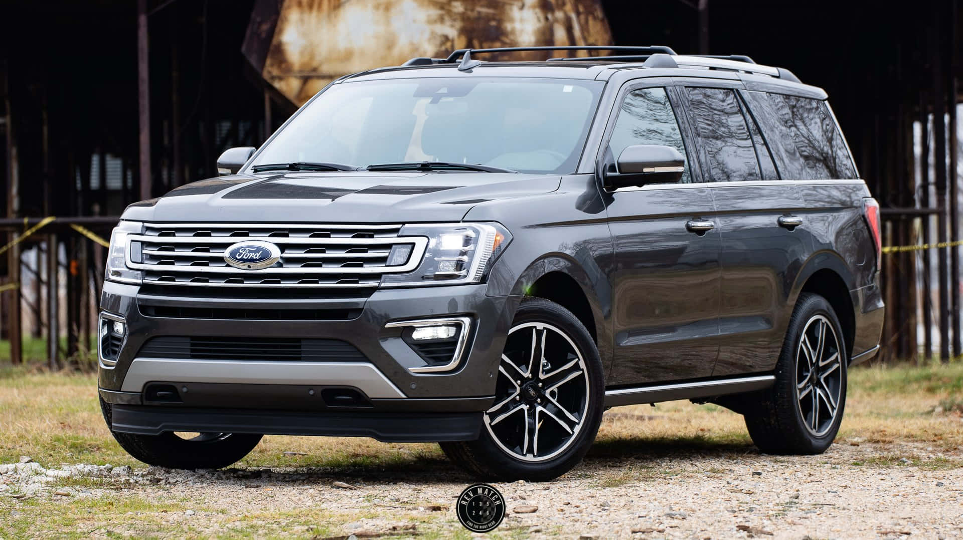 Ford Expedition 桌布 壁紙 — 一輛時尚的深灰色福特Expedition SUV停泊在碎石路上，前面是一座質樸的穀倉，帶有風化的木牆。