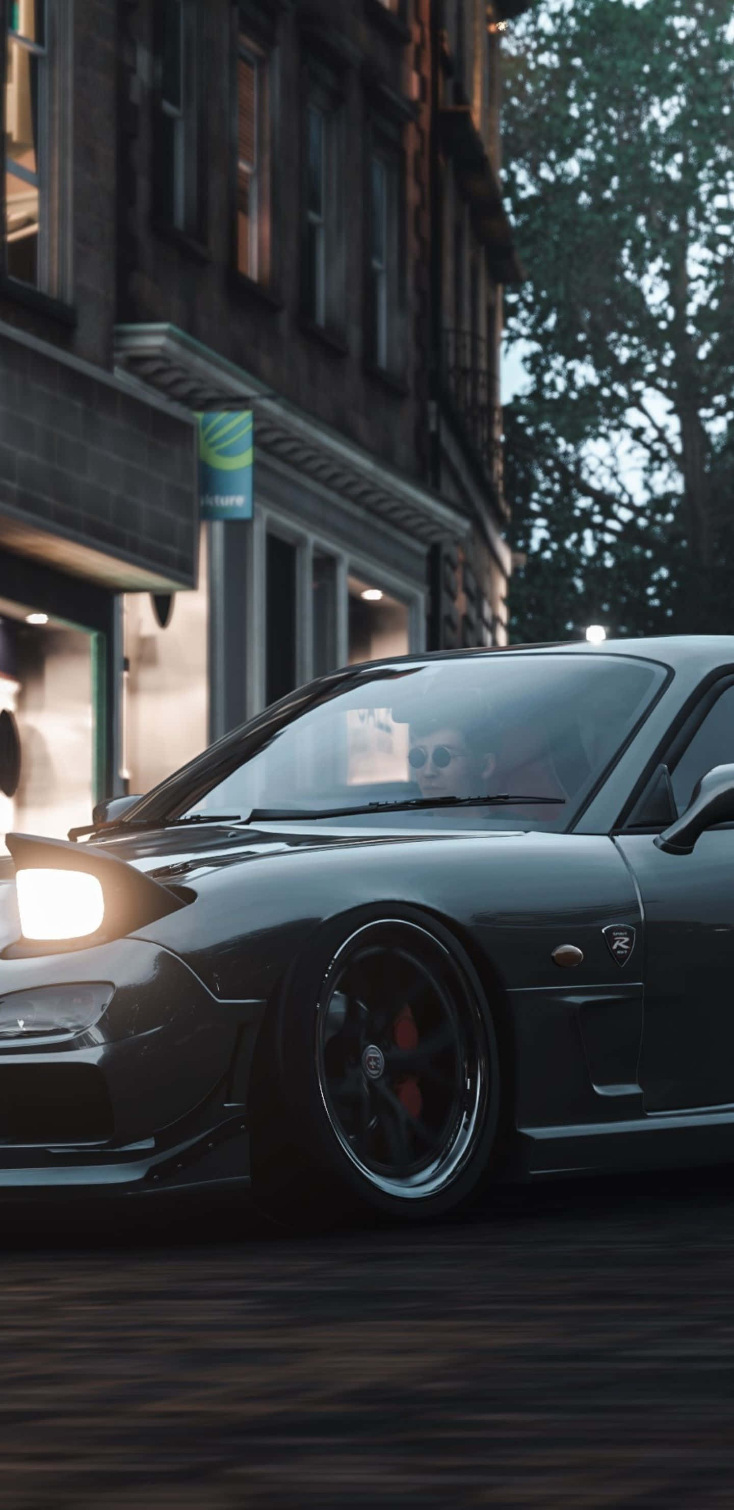 Pixel 3xl Forza Horizon 4 桌布 壁紙 — 一輛時尚的深灰色跑車，車頭燈閃閃發光，在黃昏時分載著戴太陽眼鏡的司機在城市的街道上飛馳。