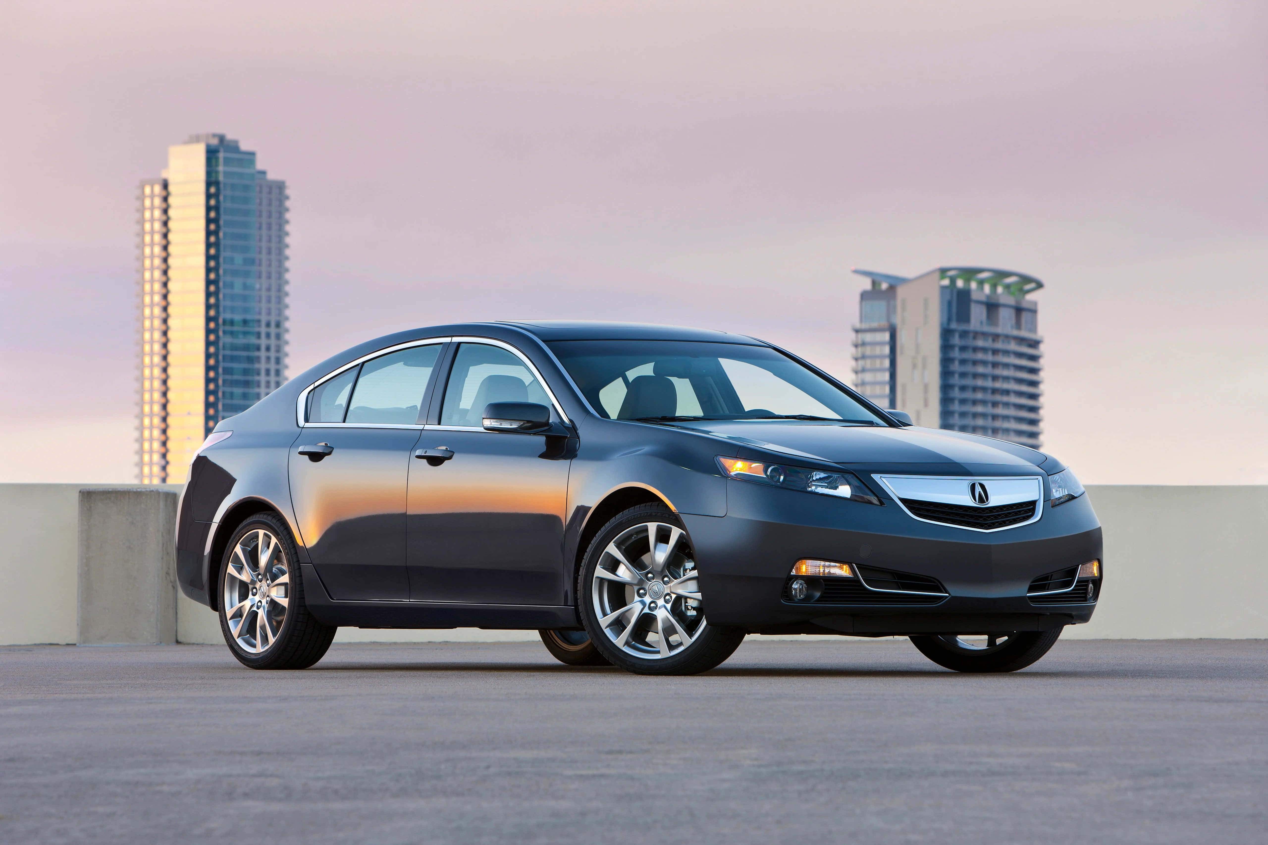 Acura 桌布 壁紙 — 一輛時尚的深灰色轎車停在天台上，現代摩天大樓在暮色中柔和地發光。