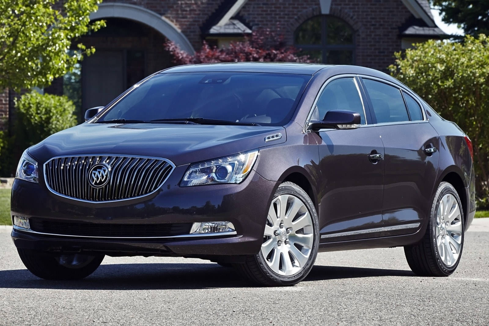 Buick 桌布 壁紙 — 一輛時尚的深紫色Buick轎車在明亮的陽光下閃閃發光，停在磚房前的車道上。
