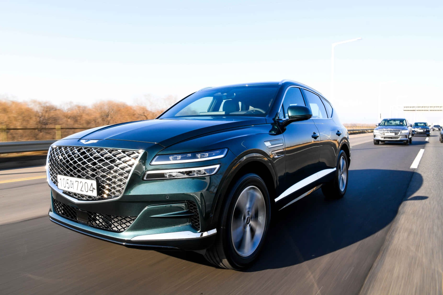 深綠色 Genesis SUV 在黃金時段行駛在高速公路上，路邊有秋天的樹木。 — Toyota Supra Mk4 壁紙