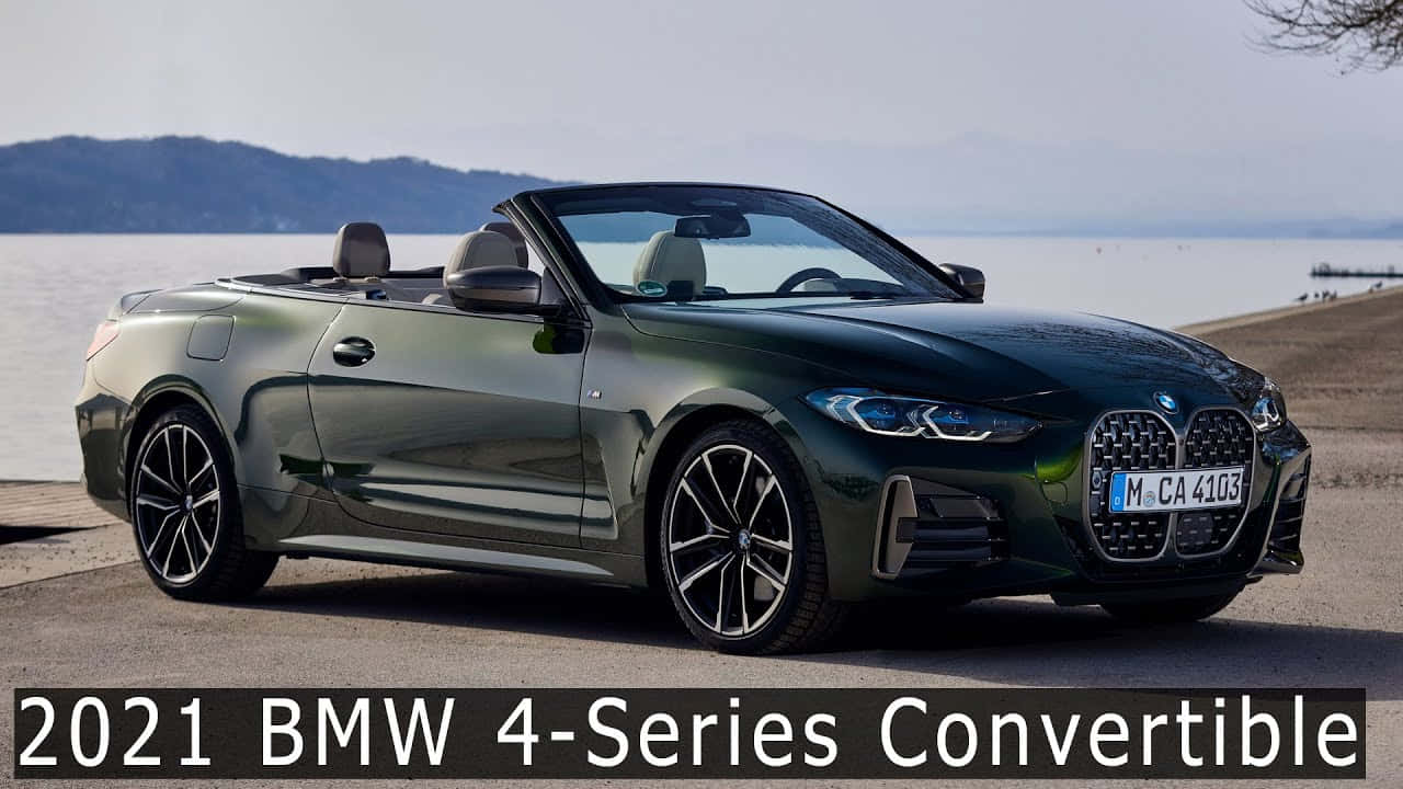 BMW 動圖 桌布 壁紙 — 一輛時尚的深綠色2021年BMW 4系列敞篷車停在平靜的湖邊，遠處有山丘，天空朦朧。