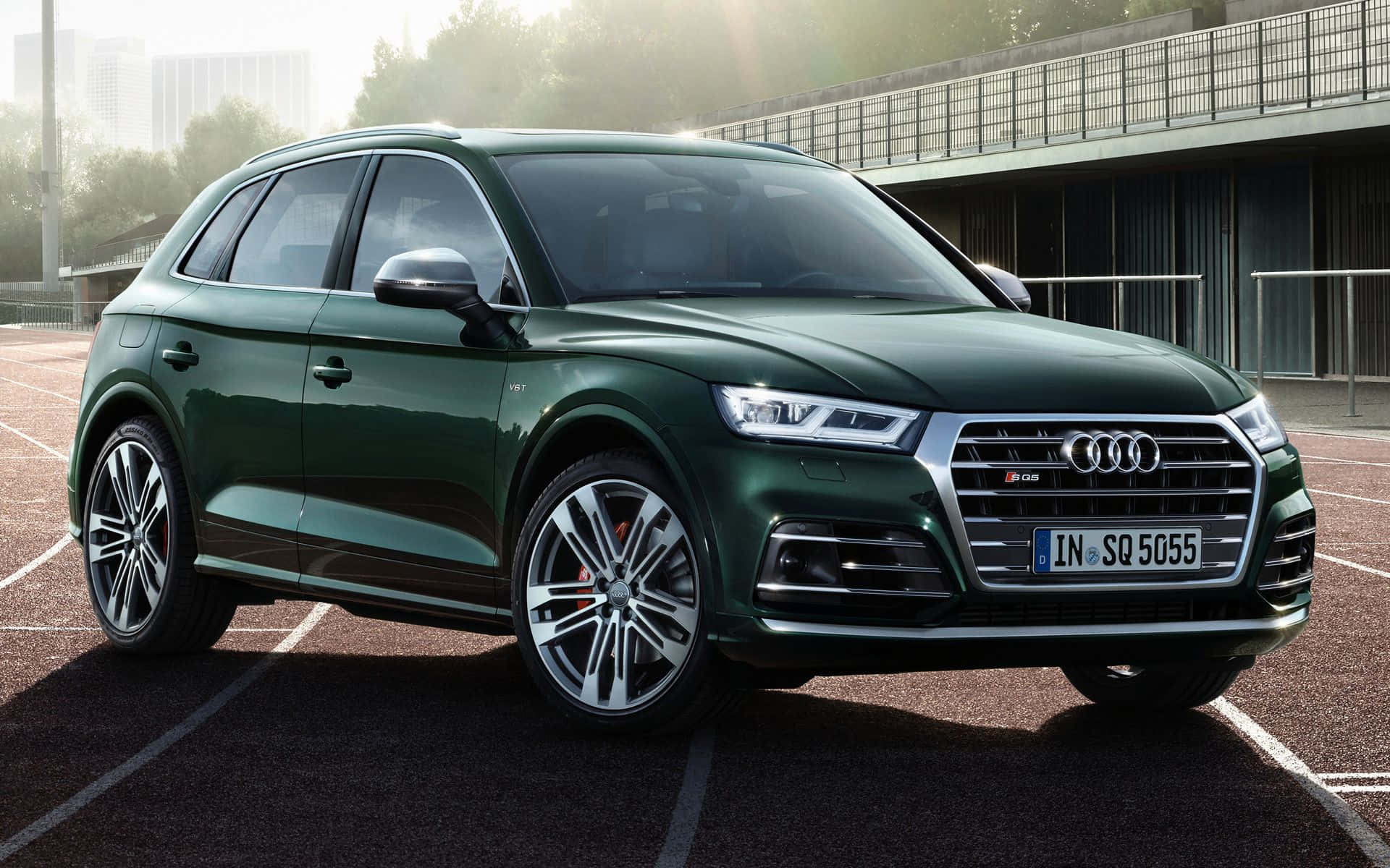Audi Sq5 桌布 壁紙 — 一輛時尚的深綠色Audi SQ5 SUV停放在陽光普照的網球場上，背景是現代建築。