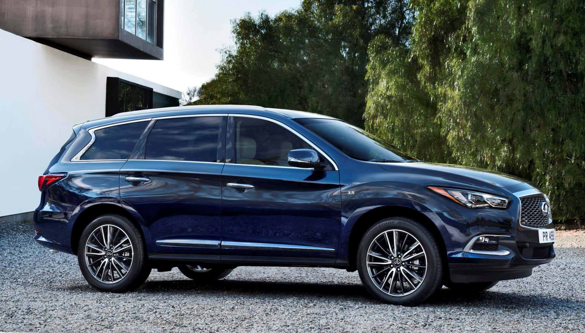 Infiniti Qx60 桌布 壁紙 — 一輛時尚的深藍色 Infiniti QX60 SUV 停放在碎石上，旁邊是一座現代白色房屋，背景是茂密的綠樹。