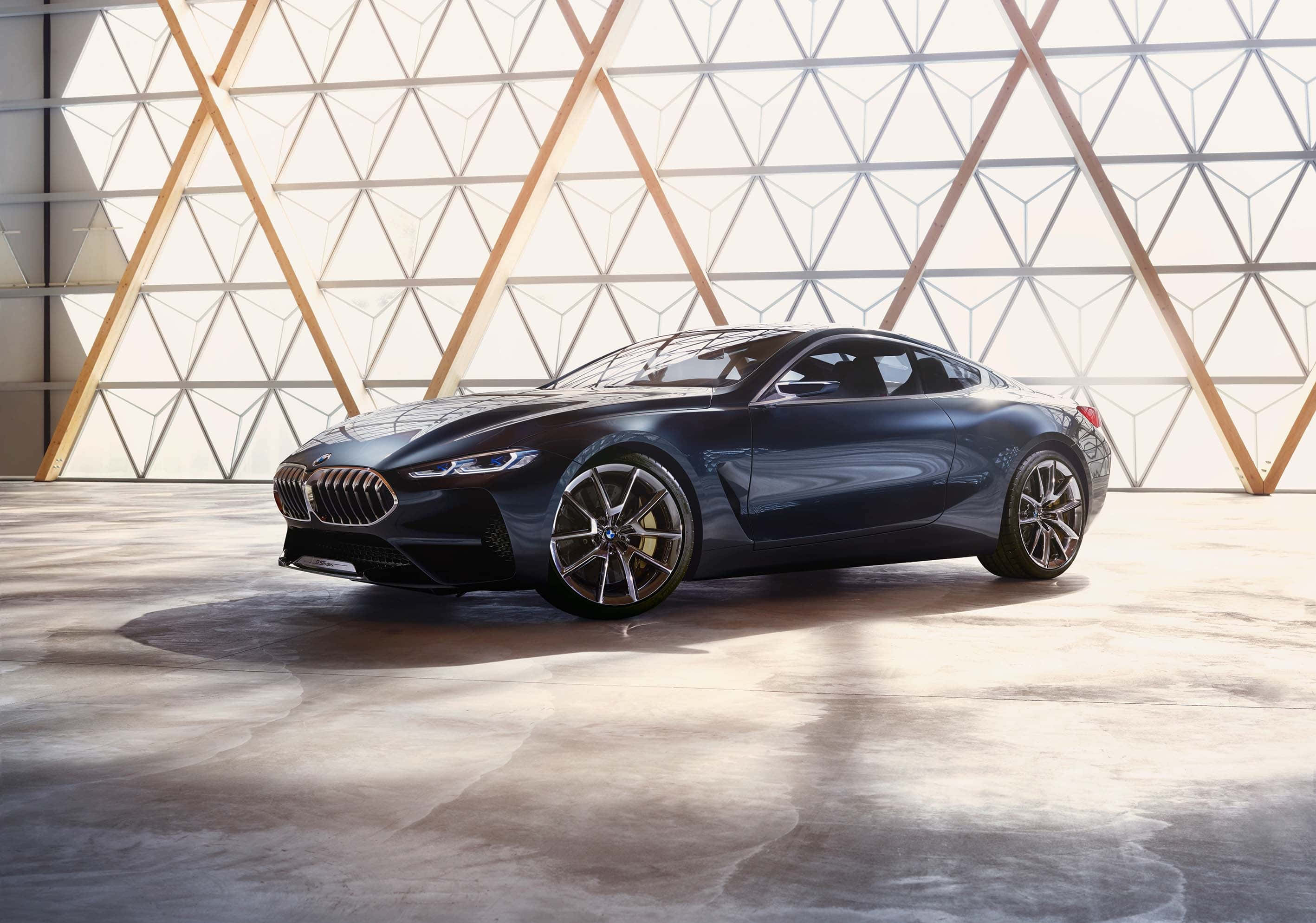 Bmw 8 Series 桌布 壁紙 — 一輛時尚的深藍色BMW概念車在現代幾何玻璃和木結構內，在明亮燈光下閃閃發光。