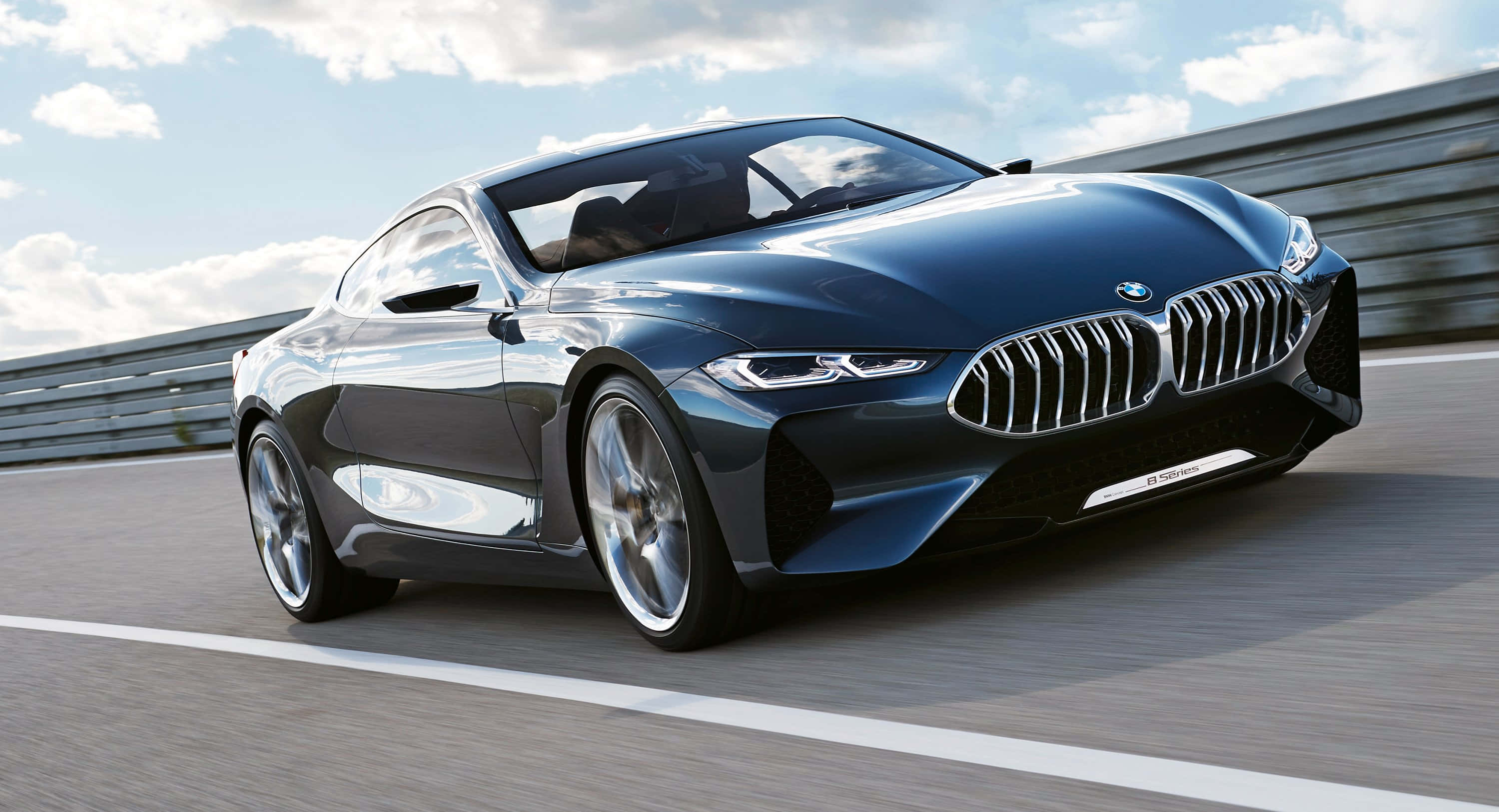 Bmw 8 Series 桌布 壁紙 — 一輛時尚的深藍色BMW概念轎跑車在陽光明媚的賽道上疾馳，帶有動態模糊和多雲的天空。