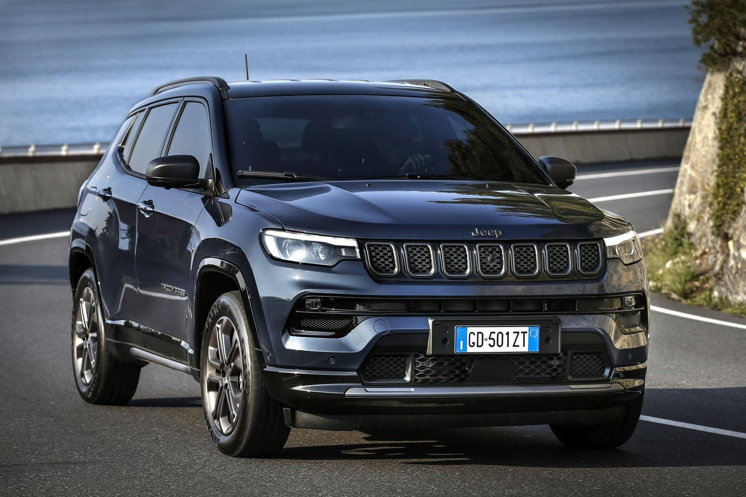 汽車 桌布 壁紙 — 一輛時尚的深藍色Jeep Compass沿著海岸道路行駛，背景是海洋和懸崖。