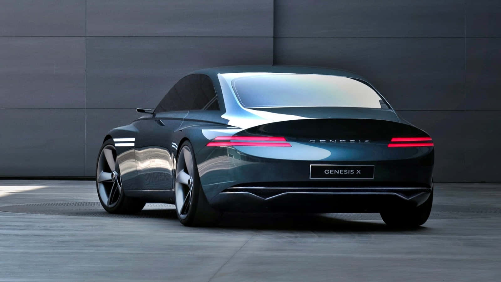 Genesis X Concept 桌布 壁紙 — 一輛時尚的深青色 Genesis X 概念車，帶有發光的紅色尾燈，停在極簡主義的灰色混凝土牆前。