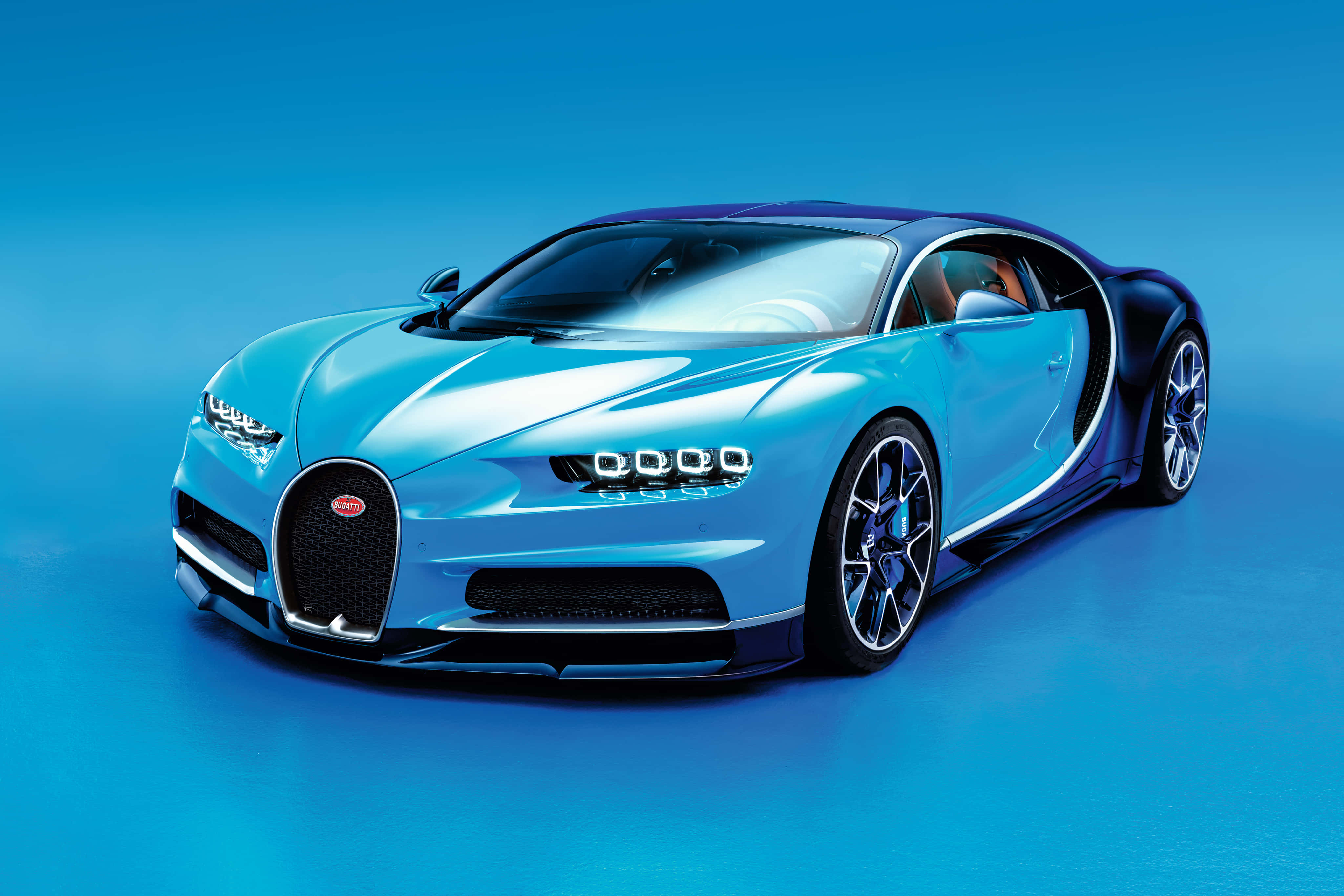 桌布 壁紙 — 一輛時尚的淺藍色Bugatti Chiron，帶有深藍色點綴，在純藍色背景下的攝影棚燈光中閃閃發光。