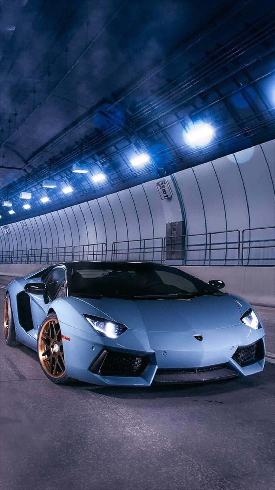 Blue Car 桌布 壁紙 — 一輛時尚的淺藍色藍寶堅尼Aventador配金色輪圈，在明亮的頂燈下穿過昏暗的工業隧道。
