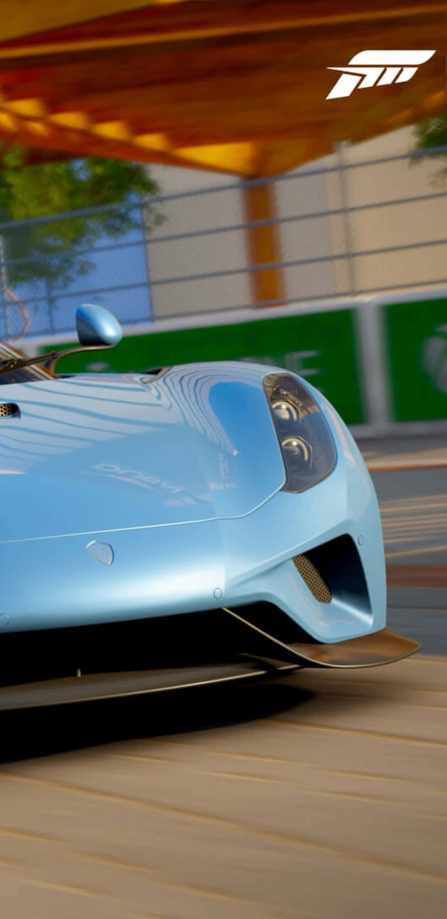 Pixel 3xl Forza Motorsport 7 桌布 壁紙 — 一輛時尚的淺藍色賽車在木製簷篷下沿著陽光普照的賽道疾馳，帶有動態模糊效果。