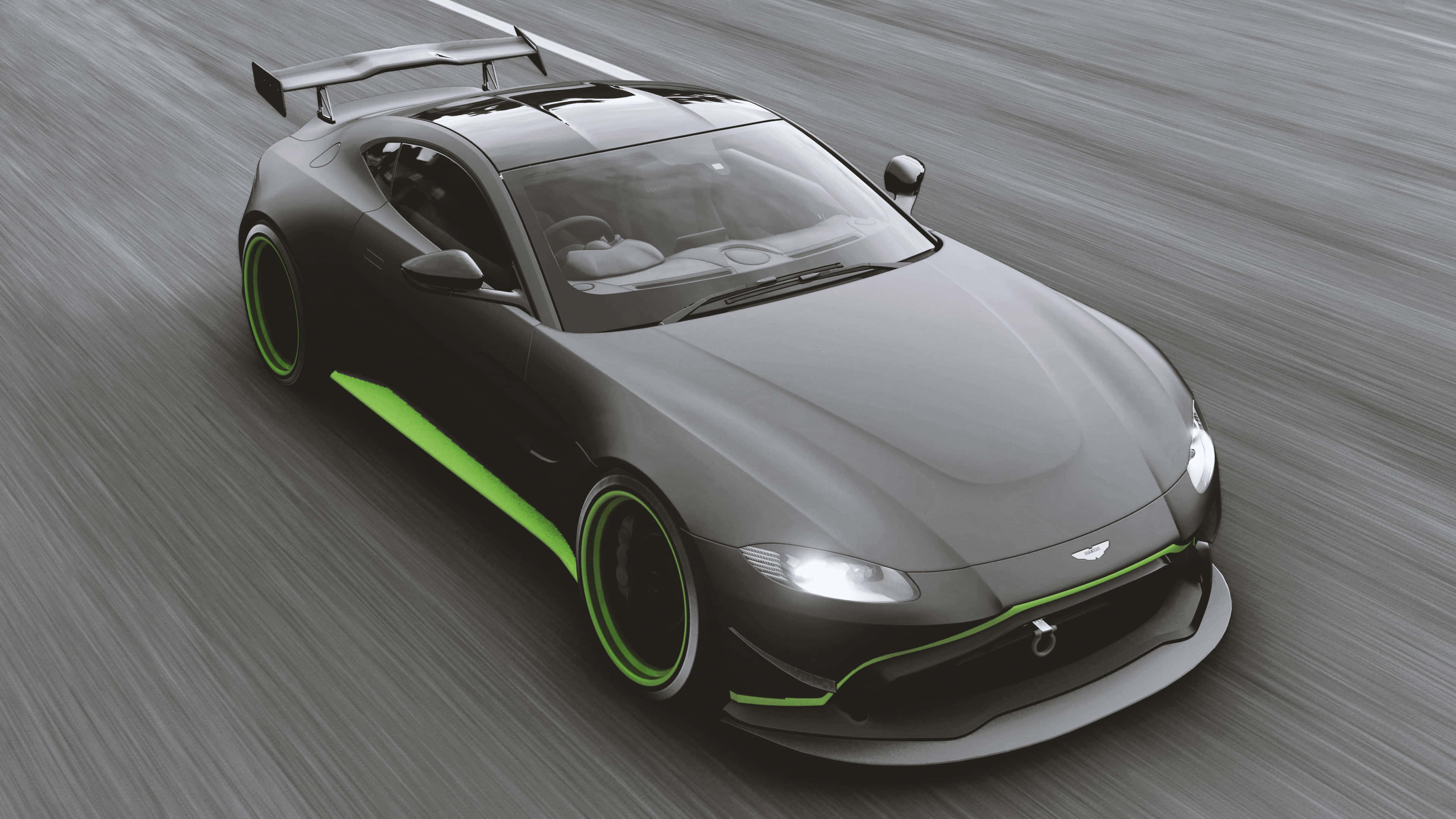 電玩遊戲 桌布 壁紙 — 一輛時尚的灰色 Aston Martin 跑車帶有鮮綠色點綴，在模糊的瀝青路上奔馳。