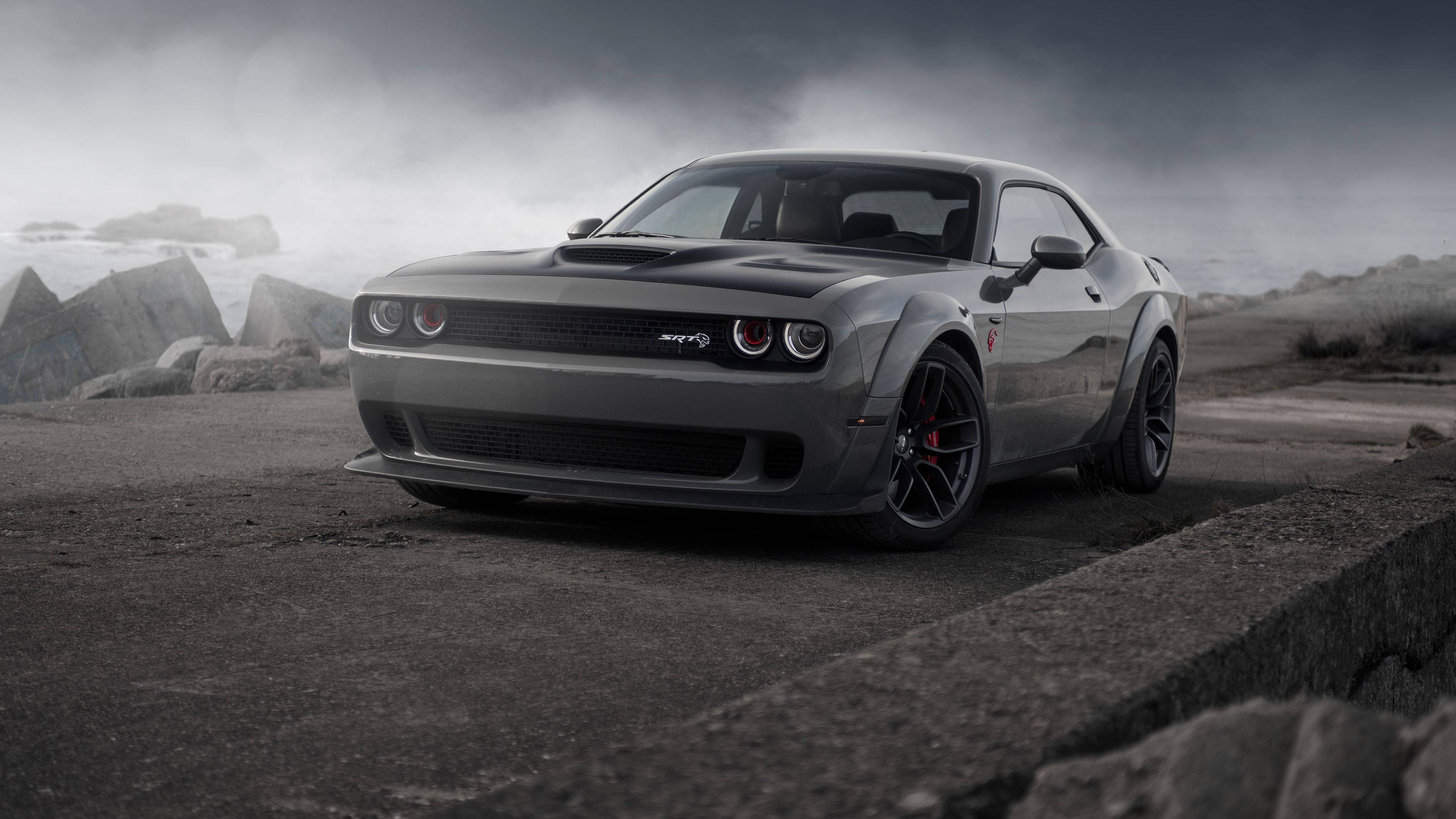Dodge 桌布 壁紙 — 一輛時尚的灰色 Dodge Challenger SRT Hellcat 停泊在崎嶇的海岸公路上，天空風暴來襲，霧氣瀰漫的海浪拍打著混凝土屏障。